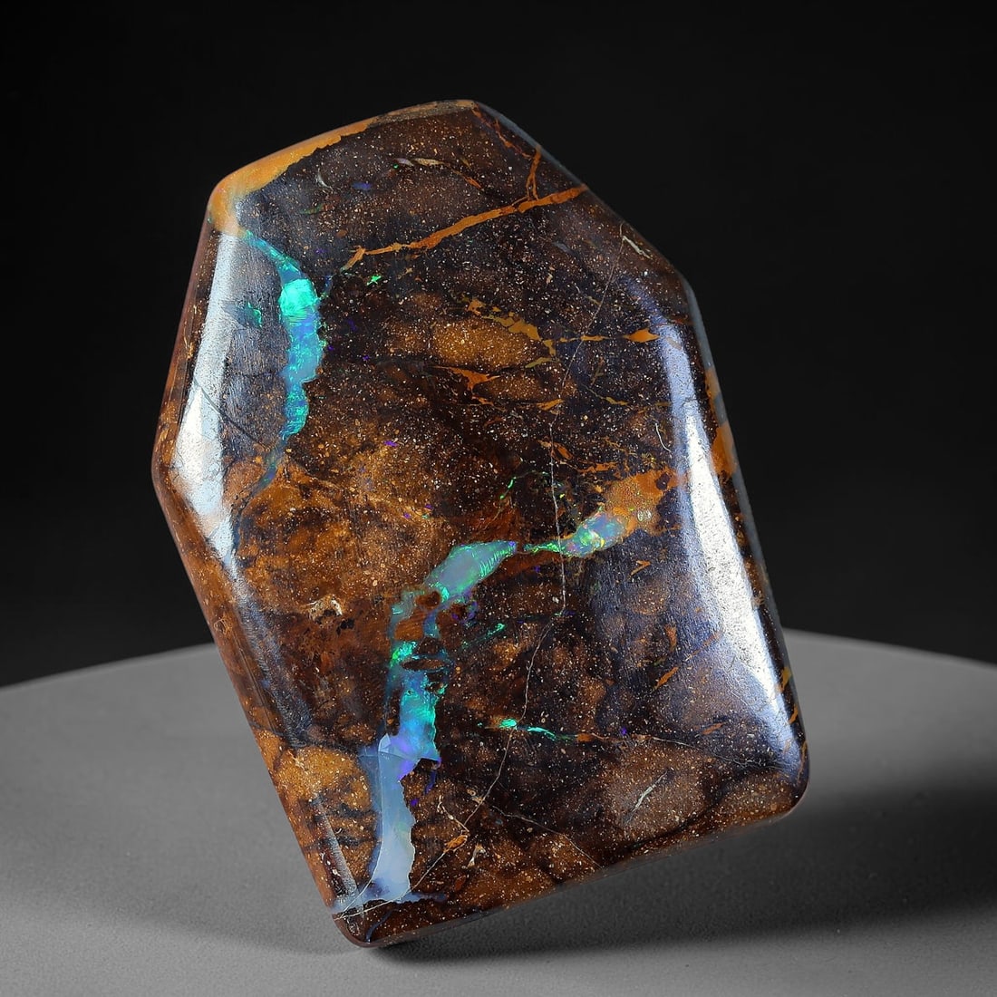 21.44ct Natural Australian Queensland Matrix Boulder Opal Freeform Hexagon Cabochon, 72AV: Hand polished soft-edged freeform hexagon cabochon of natural Queensland matrix boulder opal, featuring glitter-speckled gradient warm brown ironstone host rock marked by a prominent winding luminous 