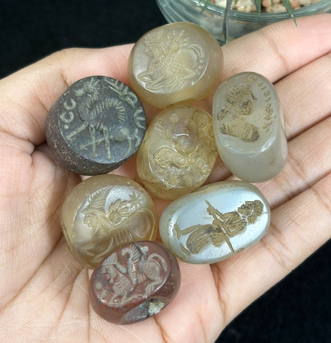 Lot of 7 Ancient Sasanian Era Chalcedony Intaglio Stamp Seal Amulets, 44YD: This seven-piece antiquity lot features hand-carved pebble stamp seals crafted from natural chalcedony in translucent amber, milky grey, deep red and dark grey stone tones. Each smooth oval and round 