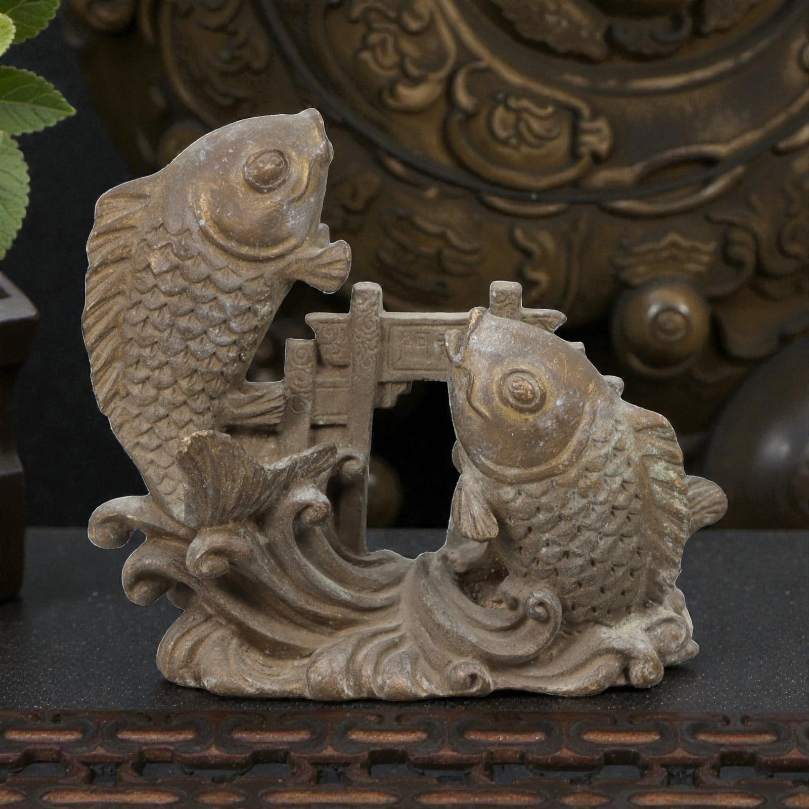 A Chinese Bronze Fish Group Display, Late Qing Dynasty, 18FH: Cast in bronze, the object is formed as a pair of stylized fish emerging from curling waves, positioned on either side of a small architectural element resembling a gate or bridge. The fish are render