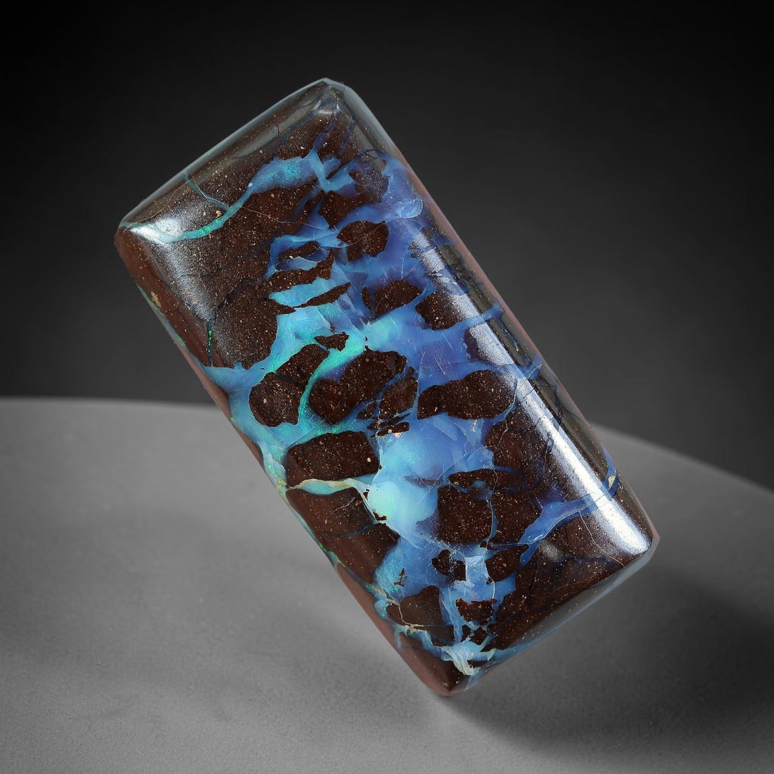 21.54ct Natural Australian Queensland Matrix Boulder Opal Cabochon, 5AV: Hand polished rectangular bar cabochon of natural Queensland matrix boulder opal, featuring dark speckled ironstone host interlaced with broad luminous opal channels blending sky blue and turquoise ir