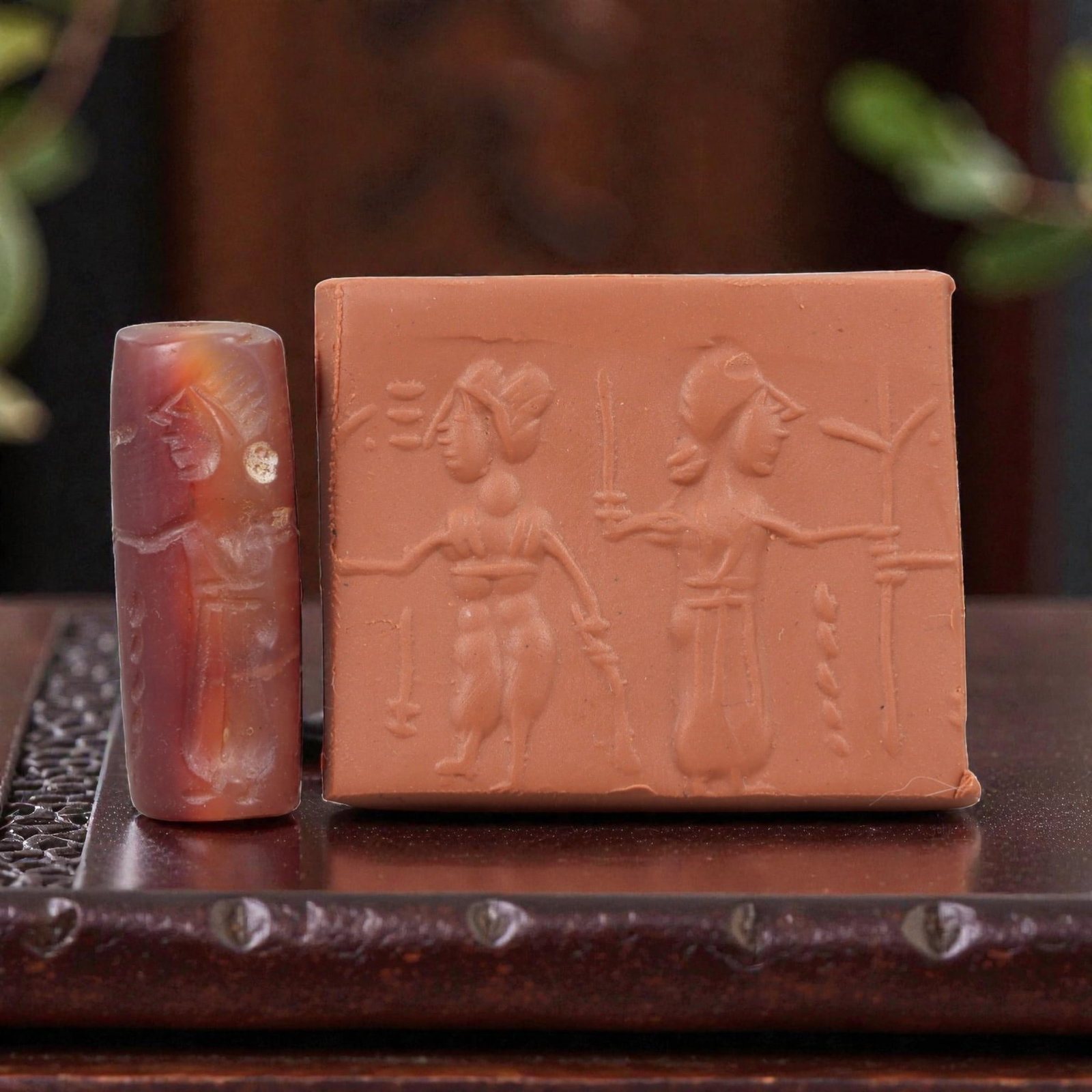 Ancient Carnelian Cylinder Seal - Mesopotamian Figural Procession Scene, 55AN: Carved from richly hued carnelian, this ancient Mesopotamian cylinder seal features a refined linear relief composition of two human figures in procession, one bearing weapons and the other extending 
