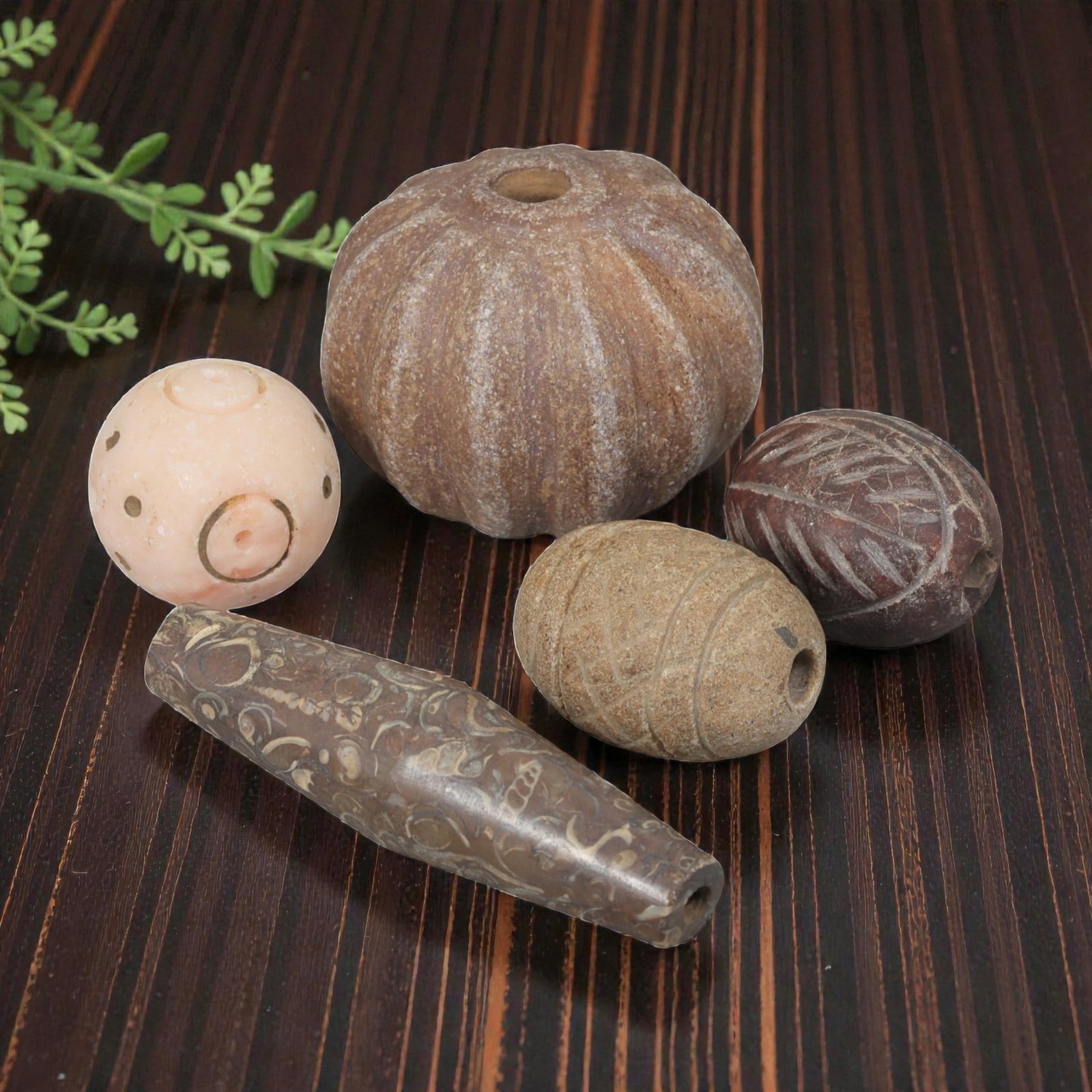 Lot of 5 Ancient Near Eastern Stone Beads, 1st Millennium BCE, 28AE: Comprising five beads of varying form and material. One spherical bead of light pink stone with incised circular and dot motifs. One large ribbed gourd-shaped bead of brown stone. One ovoid bead of br