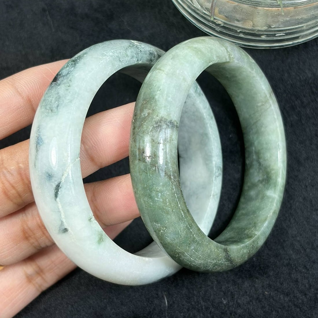 Lot of 2 Natural Burmese Type A Moss Green Jadeite Bangles, 52.6mm & 54.4mm, 27AV: Pair of fully untreated Type A jadeite bangles with inner diameters 52.6mm and 54.4mm, white and pale celadon bases naturally marked with dark mossy green floating mineral inclusions, smooth wide poli