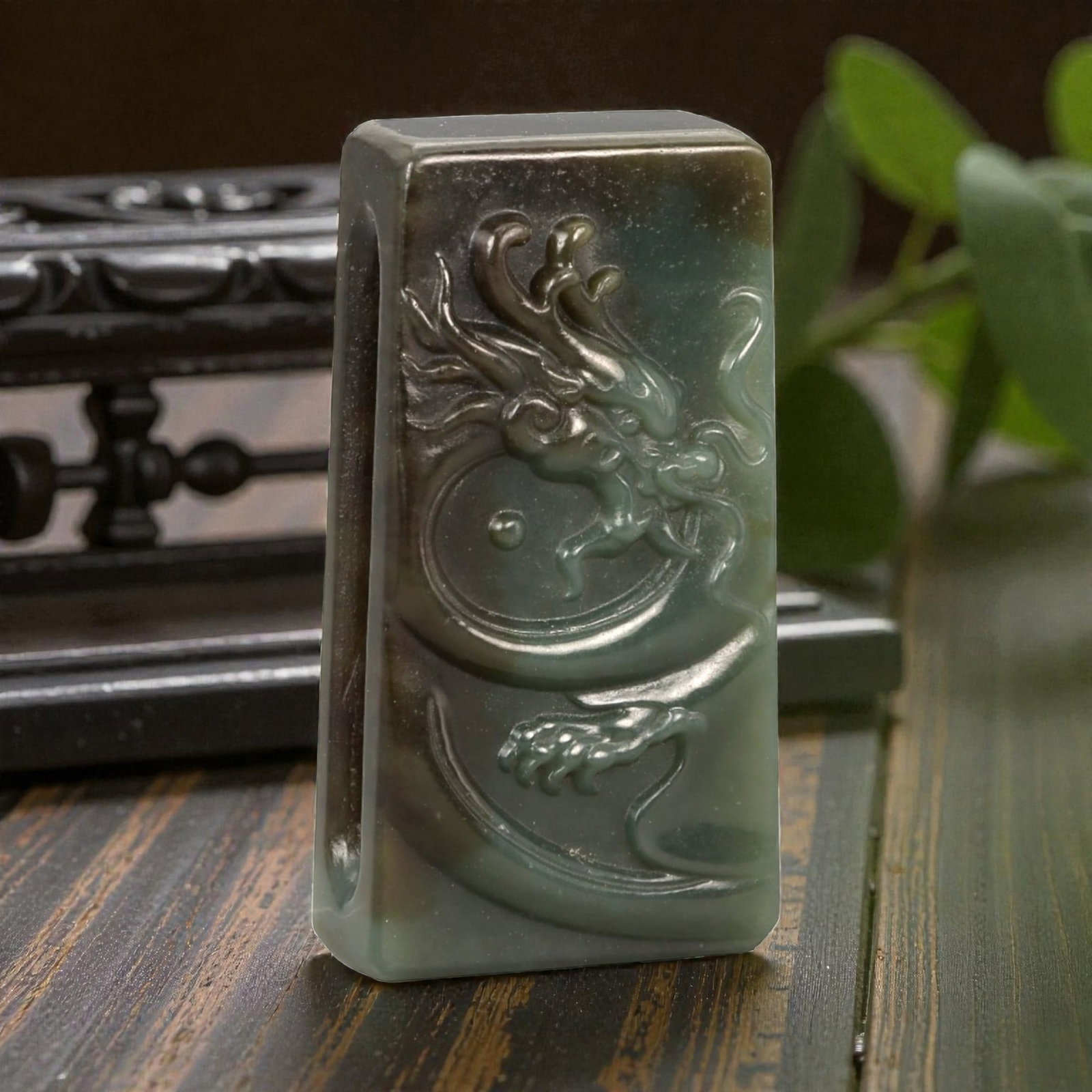 A Chinese Nephrite Jade Belt Buckle, 20th Century, 50FA: Carved from dark green nephrite jade with areas of mottled brown and olive tonal variation, the buckle is rectangular in form with slightly rounded edges and a flat reverse. The obverse is carved in l
