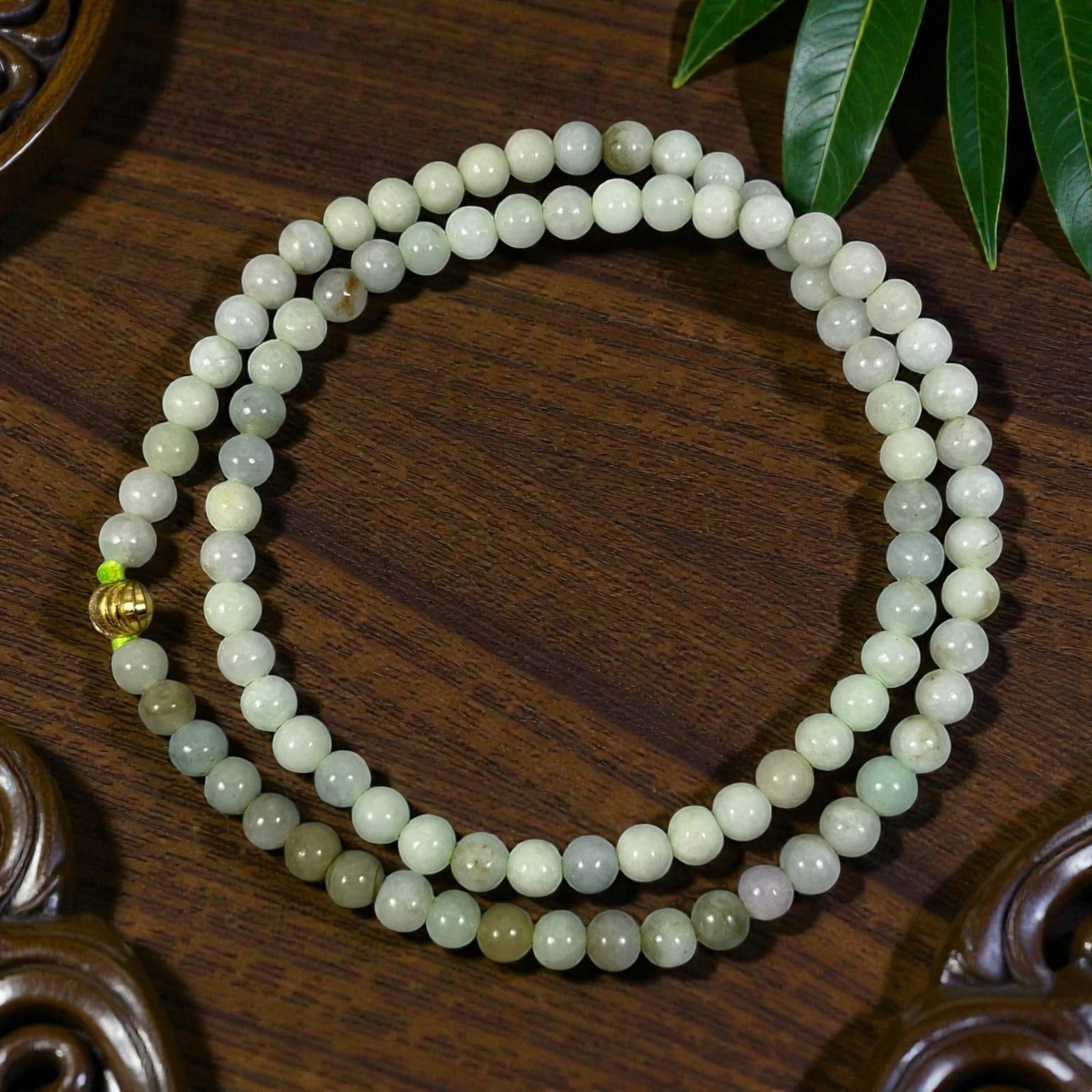 Natural Burmese Type A Jadeite Jade Bead Necklace, 98XE: A continuous strand of polished jadeite beads, each of uniform spherical form, exhibiting a range of soft pale green, white, and light grey hues with natural inclusions and subtle color variations. Th
