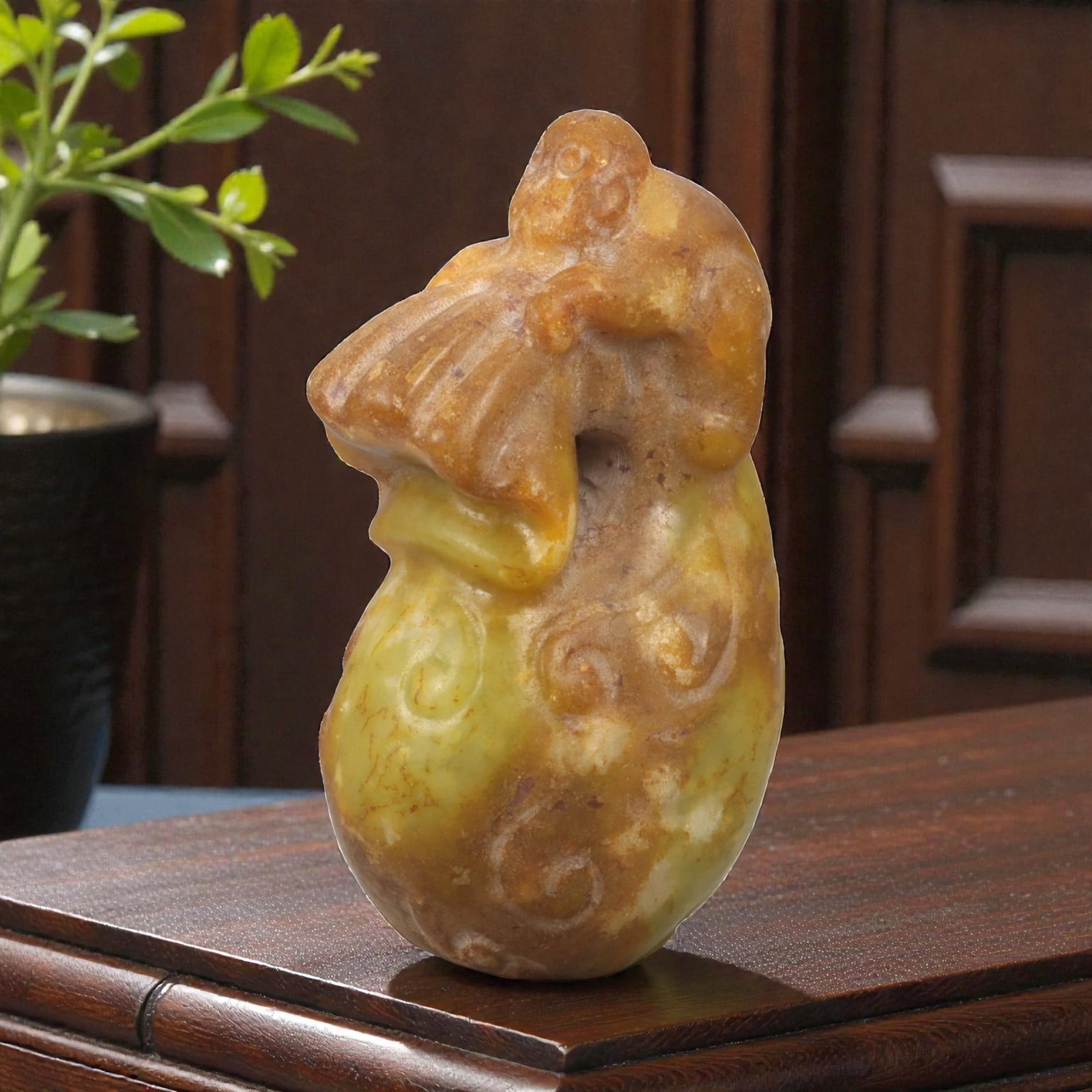 A Chinese Jade Monkey and Peach Carving, 20th Century, 80YA: Carved from translucent jade with warm honey-brown and yellow tonal variation, the sculpture is worked fully in the round as a vertical composition. The form depicts a monkey perched atop a large peac