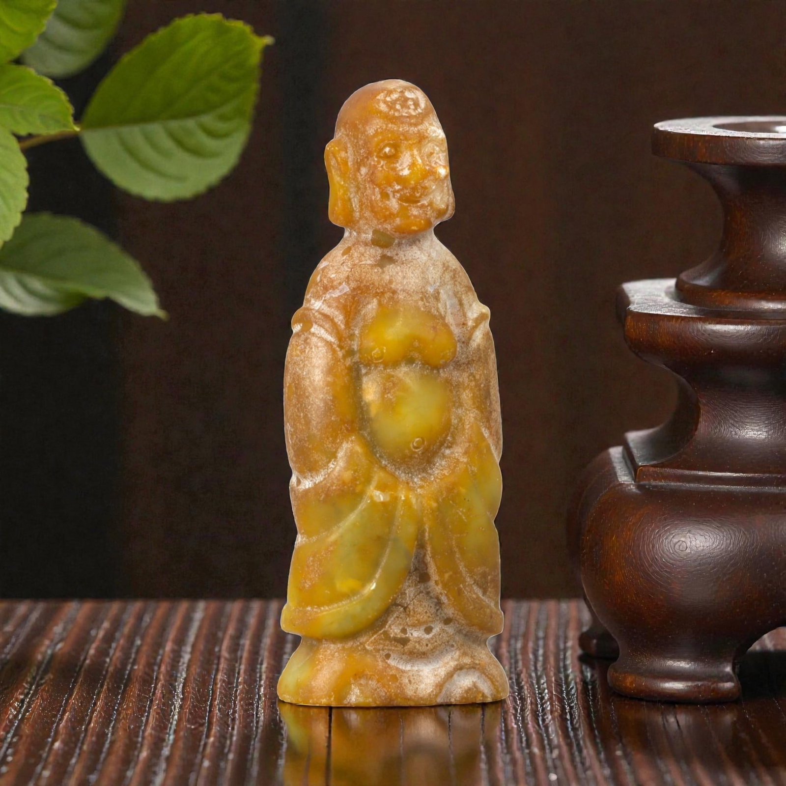 A Chinese Stone Figure of a Standing Attendant or Immortal, 20th Century, 96YA: Carved as a standing male figure, this small sculpture is worked from a warm-toned stone with mottled honey, ochre, and pale yellow inclusions, the surface showing natural translucency and areas of gr