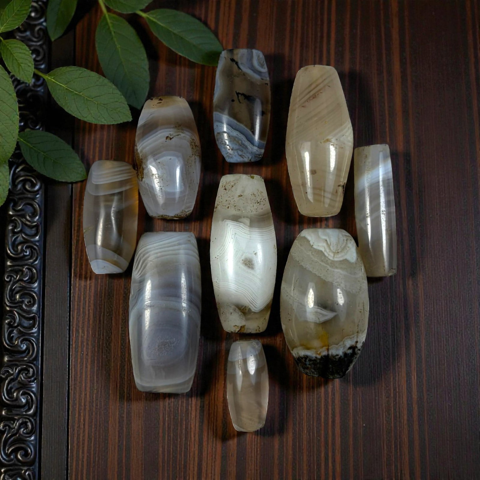 A Lot of 9 Himalayan Banded Agate Beads, Ancient to Antique Period, 23YD: Comprising lot of barrel and ovoid beads, each carved from banded agate with natural tonal variations, many displaying characteristic concentric, linear, and dendritic patterns. The surfaces exhibit s