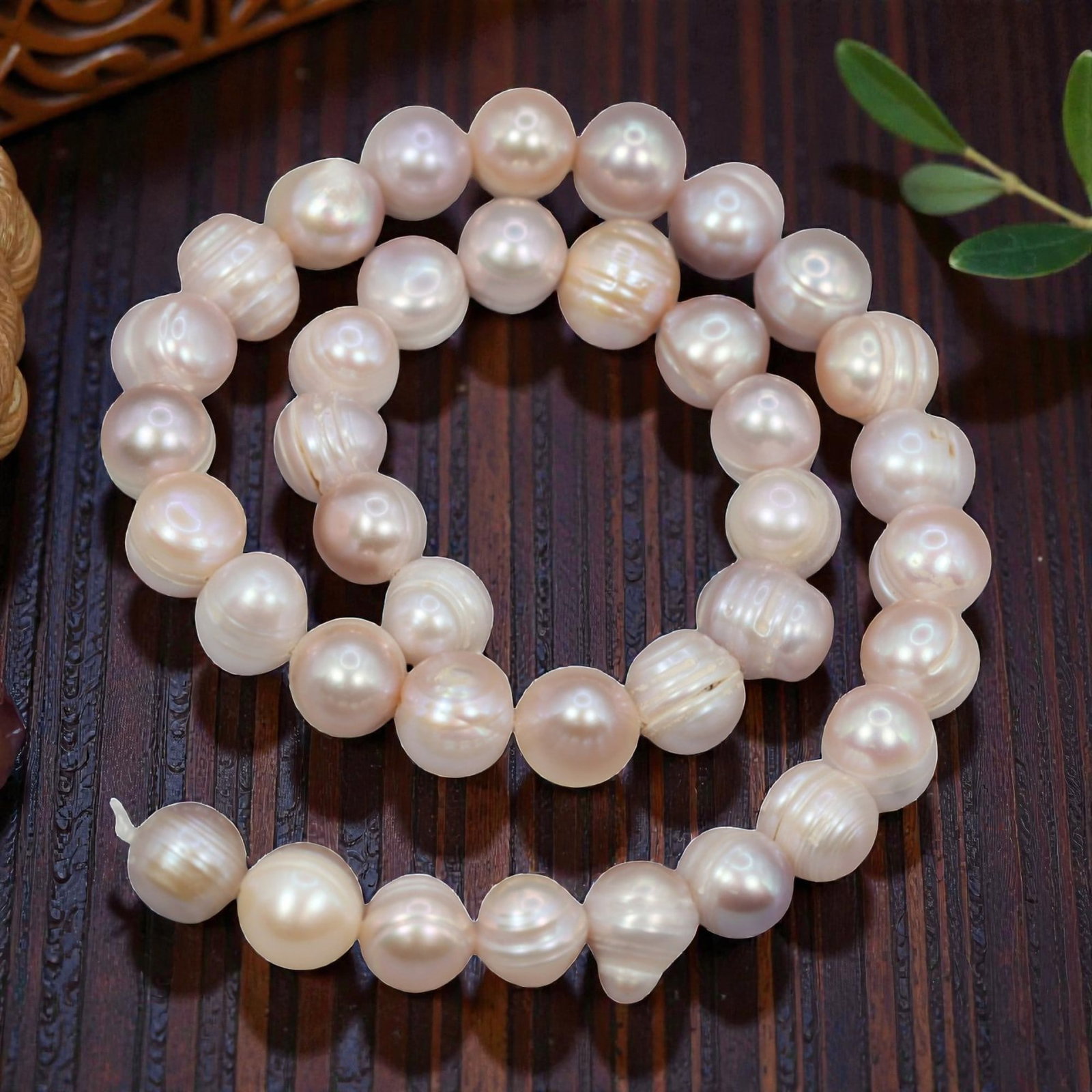 A Strand of Cultured Pearls, 20th Century, 87ZJ: Composed of near-round cultured pearls with a soft peach-pink body color and subtle iridescent overtones, the strand is strung in a single continuous line. Each pearl exhibits a smooth, lustrous surfa