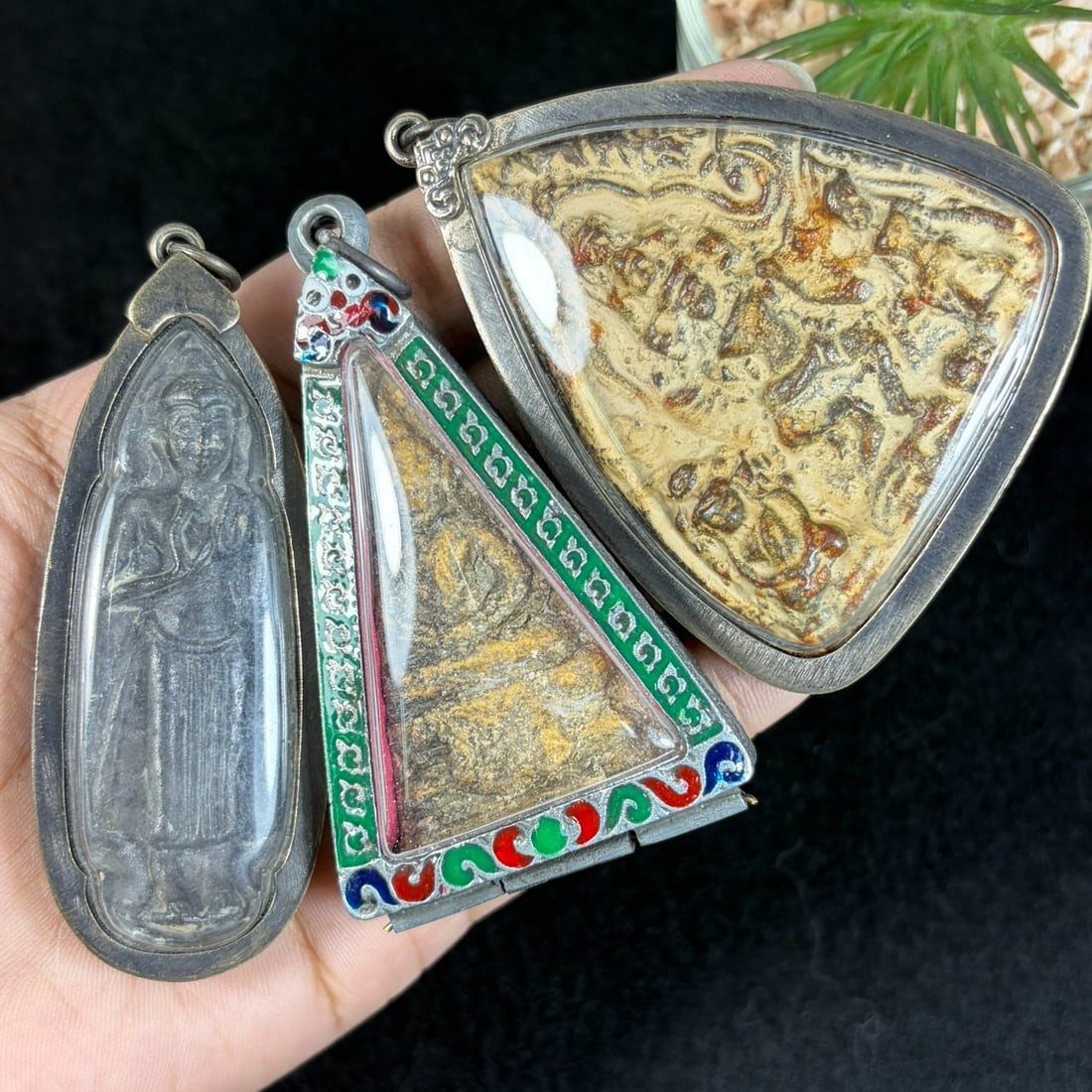 Vintage Thai Metal Cased Buddha Amulets - 3 Piece Religious Lot, 65AR: This set contains three vintage Thai Buddhist amulets each encased within untested silvered metal protective casings fitted with clear viewing panels and suspension loops for wear. Two triangular spec