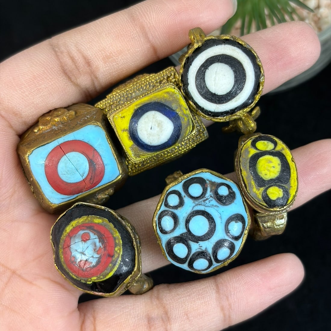 Vintage Qajar Style Gilt Glass Evil Eye Inlay Rings Lot, 92AS: This six-piece grouping features untested gilt alloy adjustable rings crafted in traditional Qajar Persian tribal style, fitted with hand-painted polychrome glass cabochons displaying classic evil eye