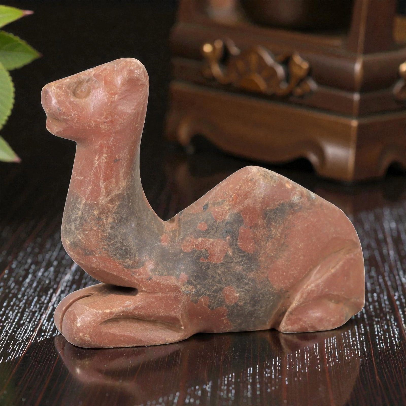 Ancient Stone Camel Effigy - Near Eastern Animal Figurine, 47AM: This camel effigy is carved from solid reddish-brown stone with natural grey veining and mineral deposits, depicting a stylized camel in a recumbent, crouched posture. The piece features clean, incise