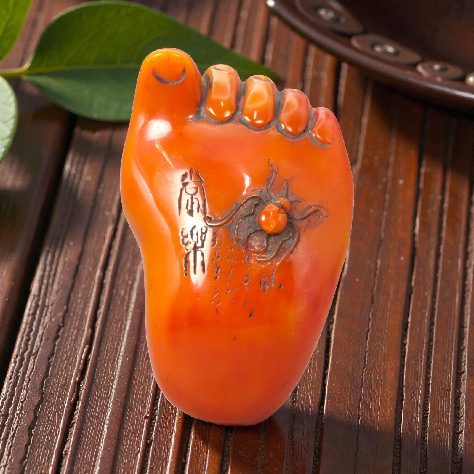 A Chinese Amber-Resin Foot-Form Carving, 20th Century, 64FC: Modeled from translucent orange-toned amber resin, the object is carved in the form of a stylized human foot, rendered in the round with simplified anatomical features. The toes are indicated in shall