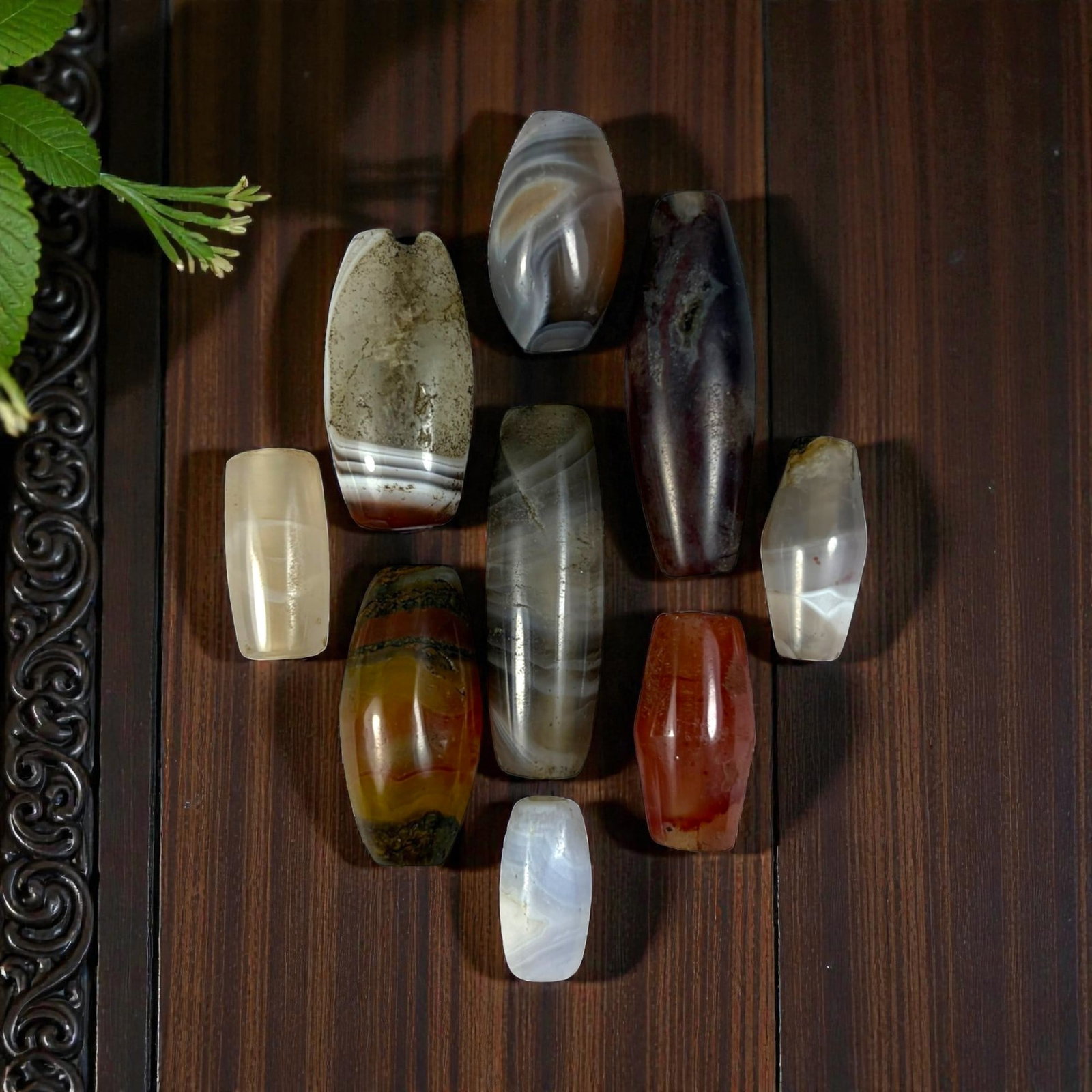 A Lot of 9 Himalayan Banded Agate Beads, Ancient to Antique Period, 18YD: Comprising lot of barrel and ovoid beads, each carved from banded agate with natural tonal variations, many displaying characteristic concentric, linear, and dendritic patterns. The surfaces exhibit s