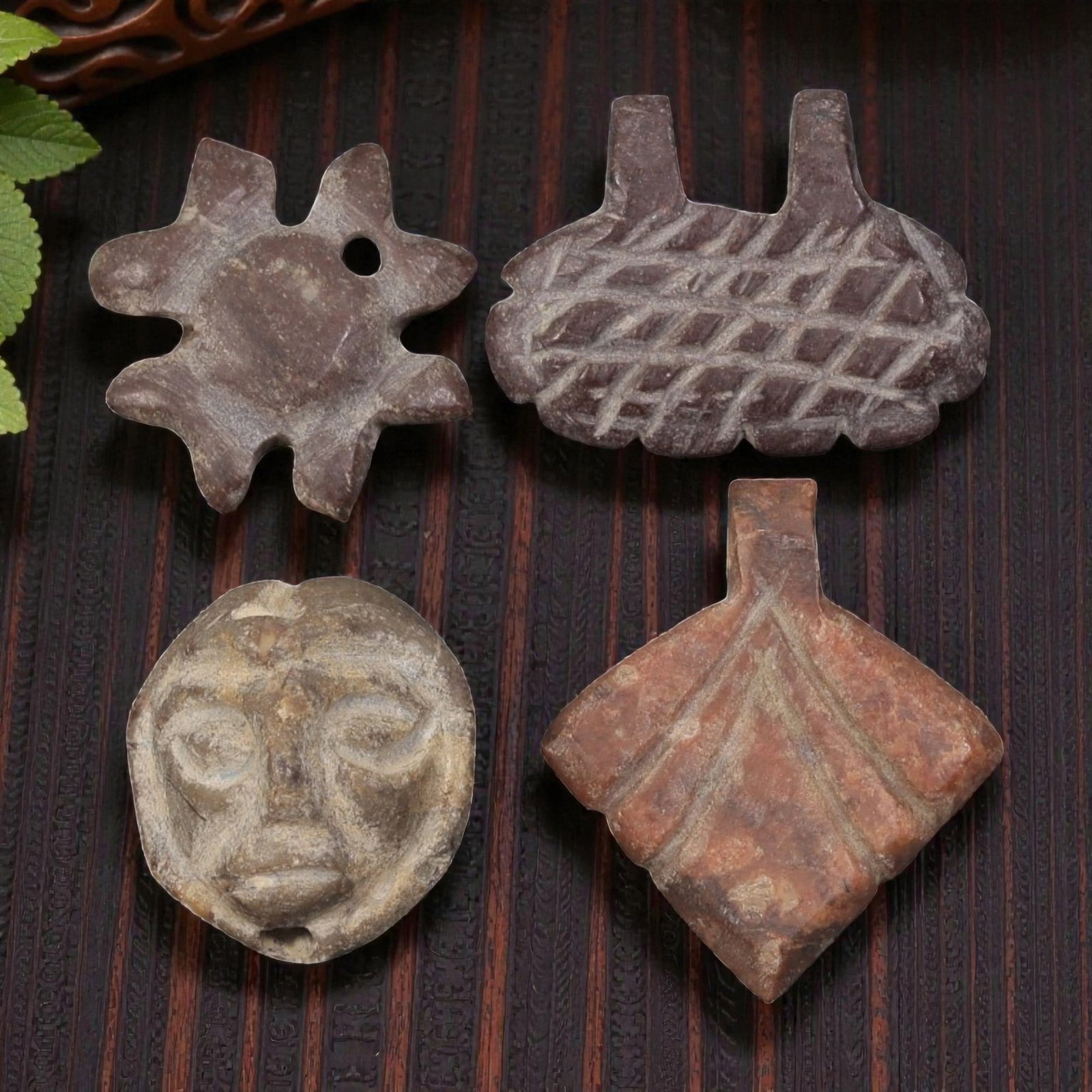 Lot of 4 Ancient Coptic Egyptian Red Stone Amulets, Circa Roman to Coptic Era, 16AE: The group comprises four small carved stone amulets in varying reddish-brown and brown tones. One example is star-shaped with a central disc and a perforation for suspension. A second is a basket-like