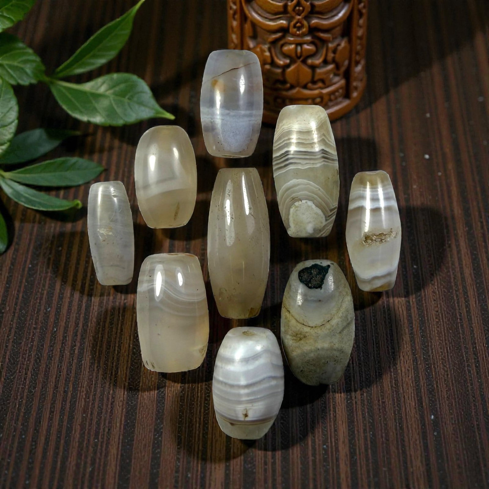 A Lot of 9 Himalayan Banded Agate Beads, Ancient to Antique Period, 28YD: Comprising lot of barrel and ovoid beads, each carved from banded agate with natural tonal variations, many displaying characteristic concentric, linear, and dendritic patterns. The surfaces exhibit s
