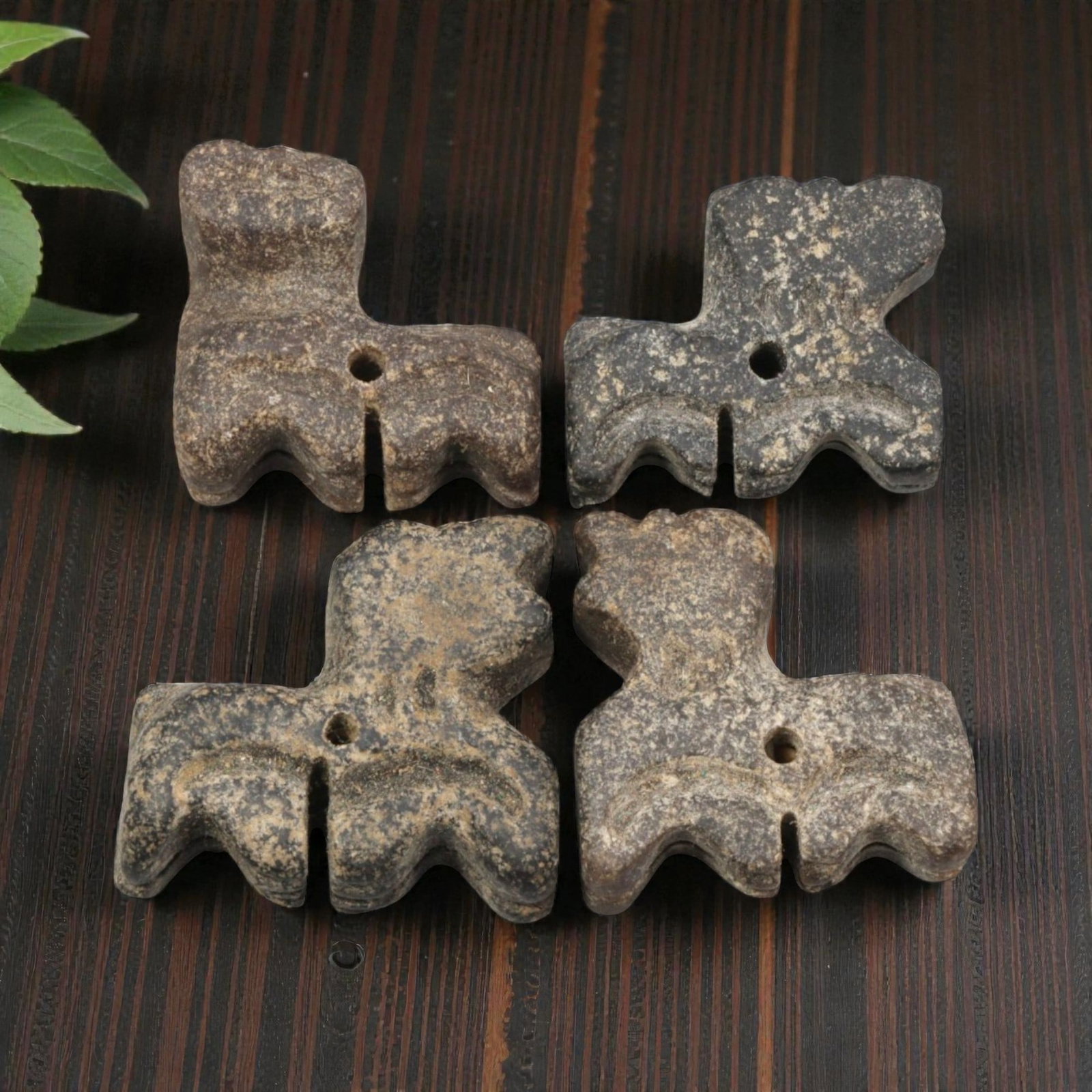 Lot of 4 Ancient Bactrian Zoomorphic Feline Stone Amulets, 39AH: A set of four ancient zoomorphic amulets, hand-carved from dark grey speckled stone, characteristic of Bactrian (Central Asian) craftsmanship. Each piece depicts a stylized feline figure with a compac