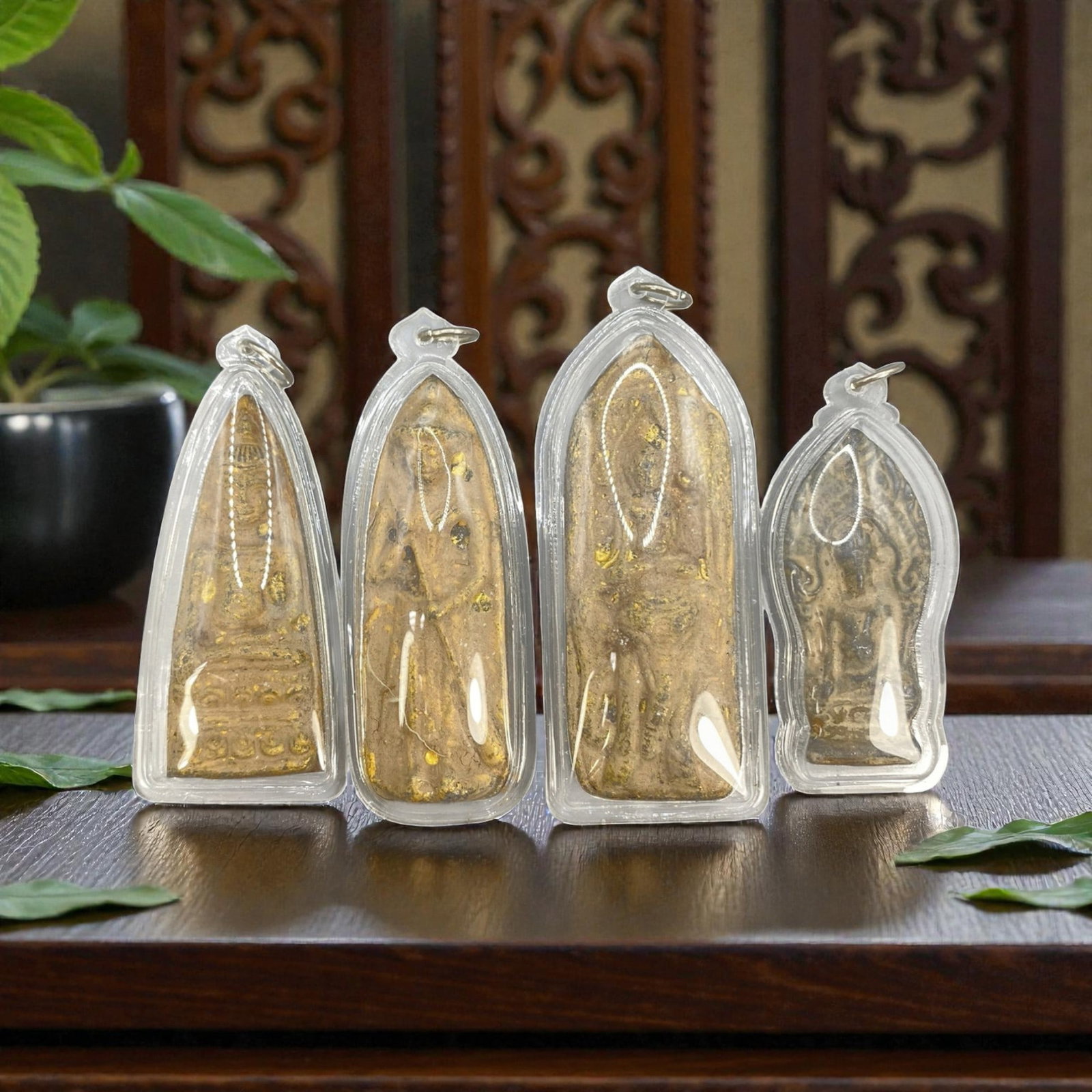 A Lot of 4 Vintage Thai Buddhist Amulets in Clear Cases, 12WT: A curated lot of four vintage Thai Buddhist amulets, each housed in a clear protective plastic case with a suspension loop. The amulets depict standing Buddha figures, with varying finishes including 
