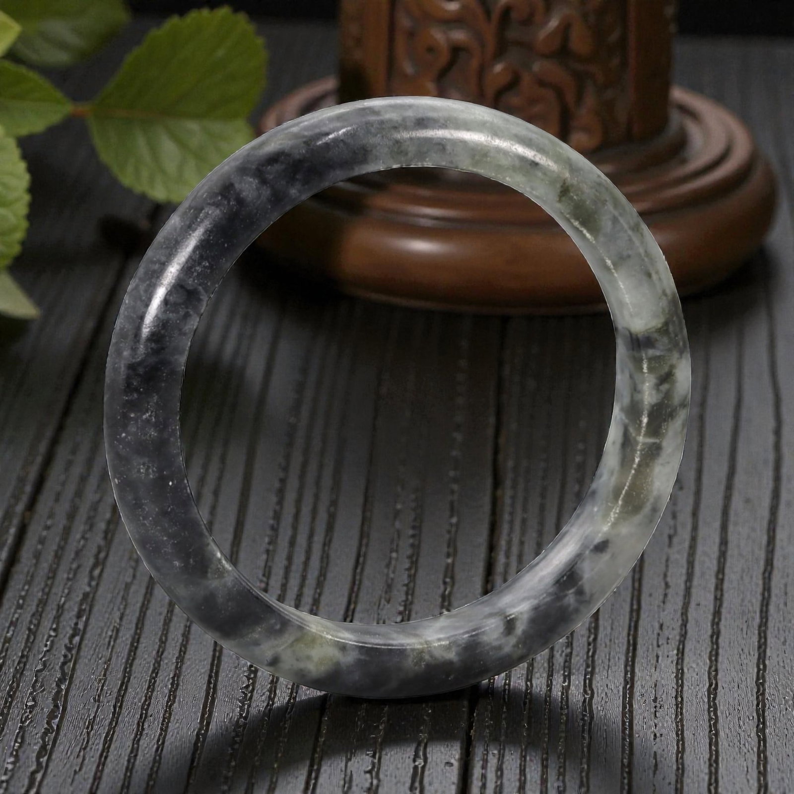 Natural Burmese Type A Jadeite Jade Bangle Bracelet, 20th Century, 97ZK: Carved from jadeite jade with a deep greyish-black base and subtle pale grey marbling throughout, the bangle is formed as a solid, continuous circular band with a classic rounded cross-section. The su