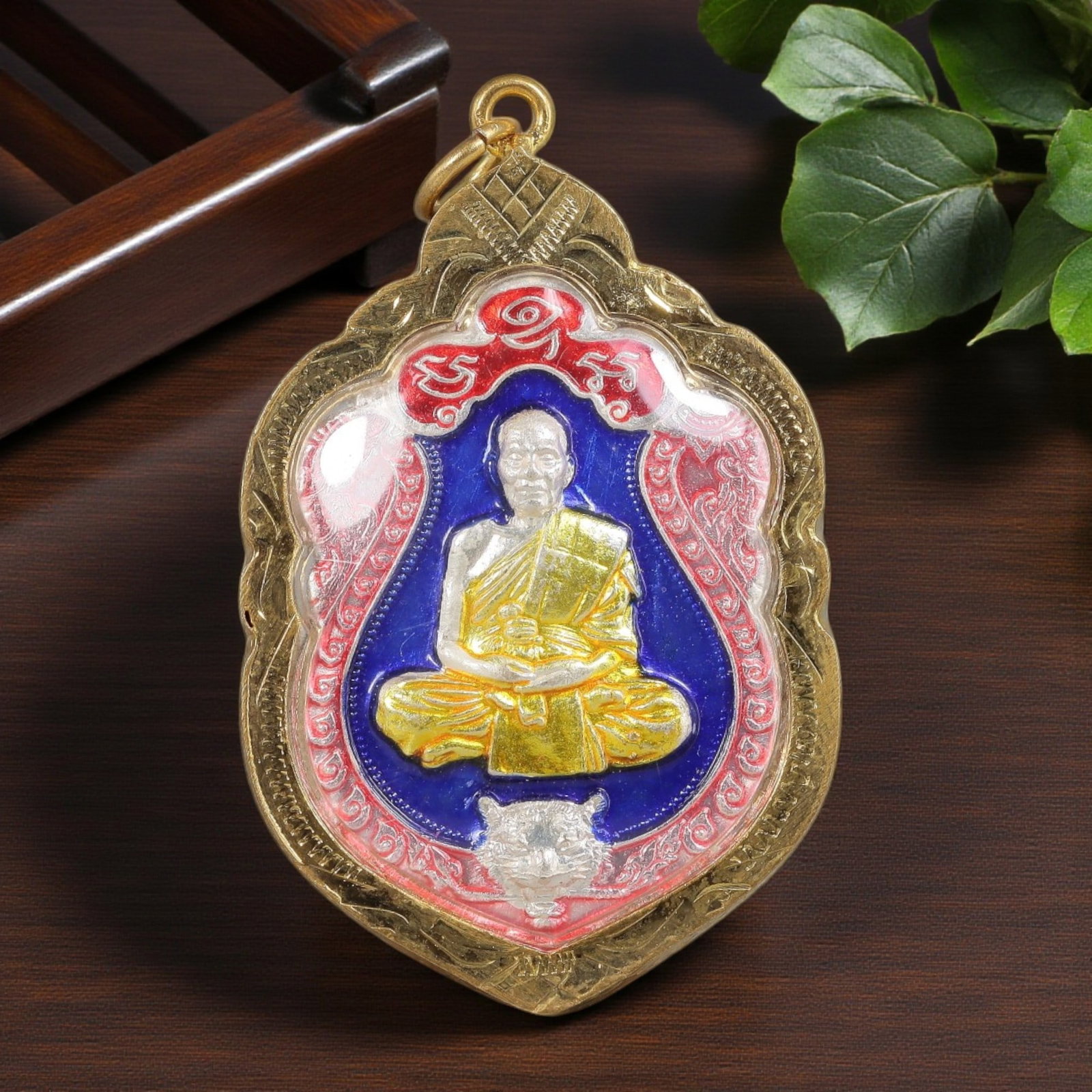 Thai Monk Amulet - Enamel Gold Tone Pendant, 53ZB: A Thai Buddhist monk amulet featuring a seated revered figure with a tiger motif, housed in an ornate gold-tone metal casing. The glass-fronted enclosure protects the colorful enamel plaque, which dis