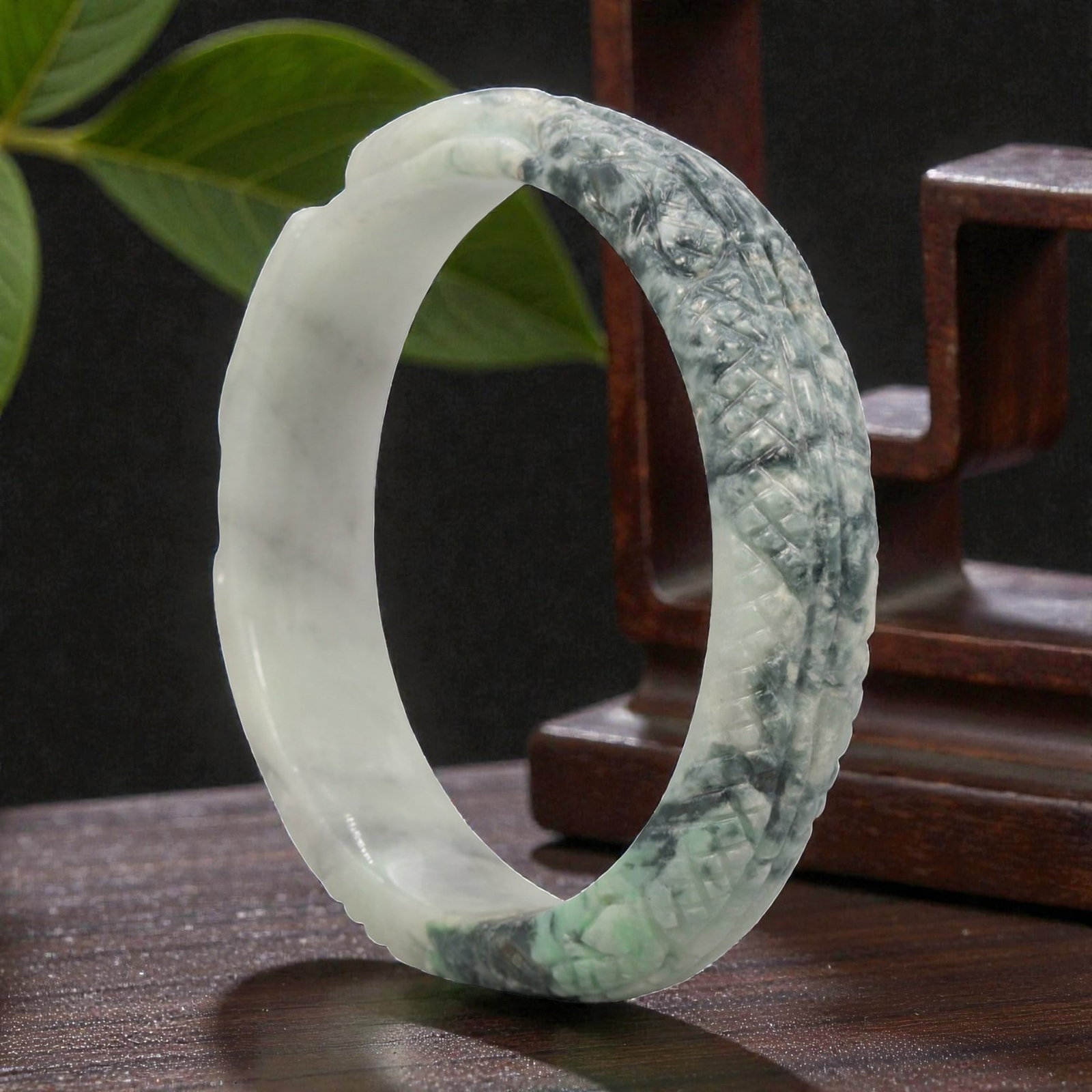 Natural Burmese Type A Carved Jadeite Jade Bangle Bracelet, 20th Century, 27ZL: A fine jadeite bangle of circular form, masterfully carved in relief with a continuous band of a sinuous dragon coiling around its circumference. The stone exhibits a striking variegated palette, with