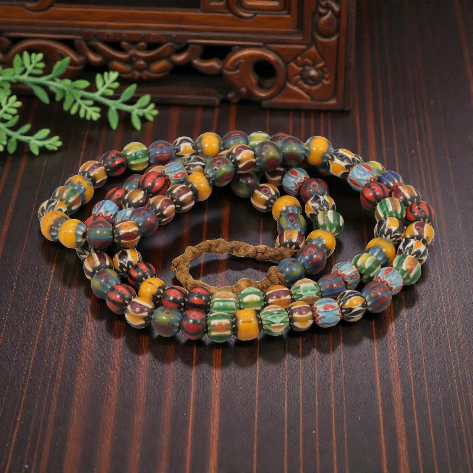 Strand of Antique Chevron Glass Beads, Unstrung, 21AH: A single strand of unstrung antique chevron glass beads, measuring approximately 33 cm in length. The strand features round beads with intricate multicolored chevron patterns, characteristic of tradit