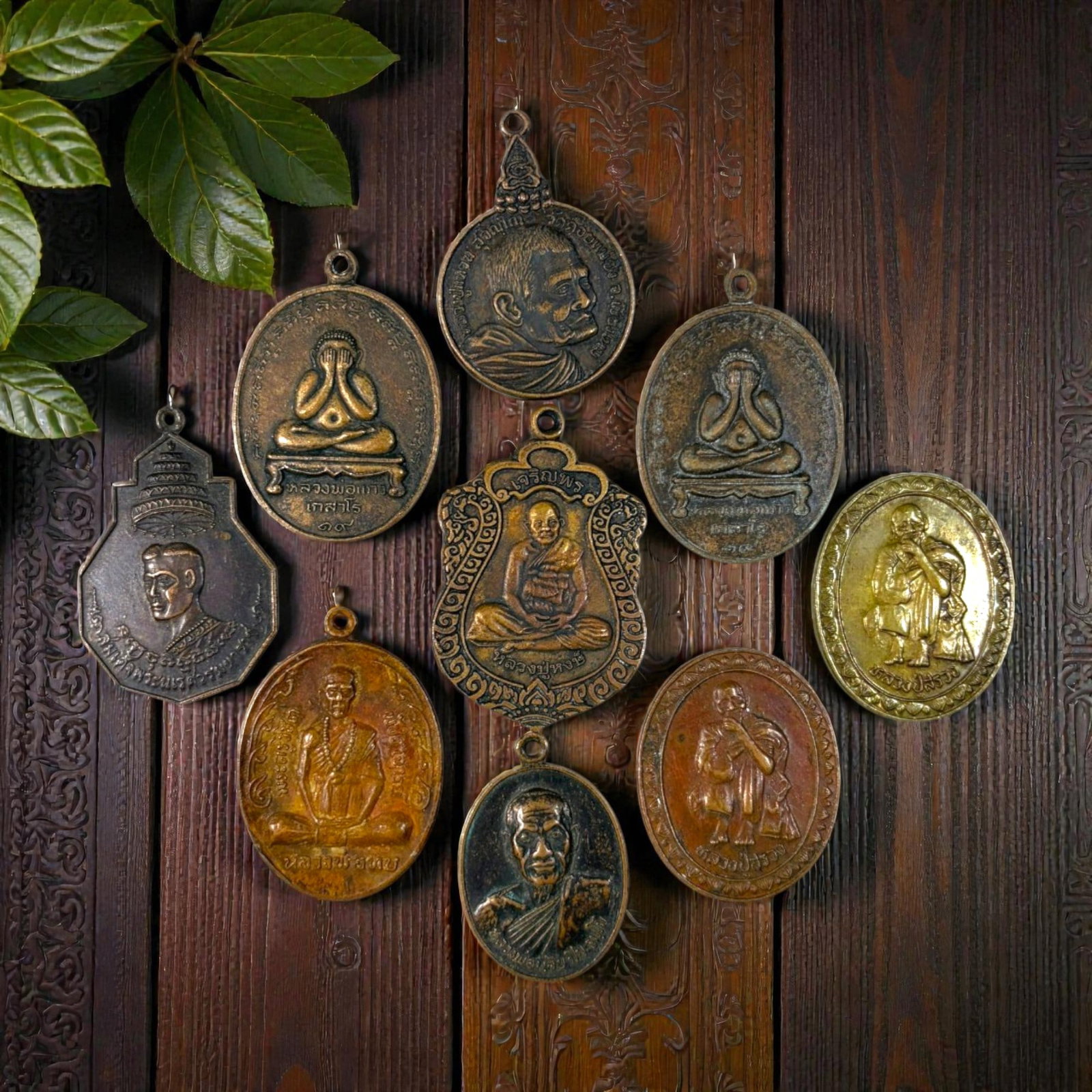 A Lot of 9 Vintage Thai Copper and Bronze Amulets, 47AA: Comprising 9 unmounted pendants ranging from 3 to 4.5 cm in height. The collection features a diverse array of cast metal amulets, including revered monastic portraits, iconic Phra Pidta (closed-eye B
