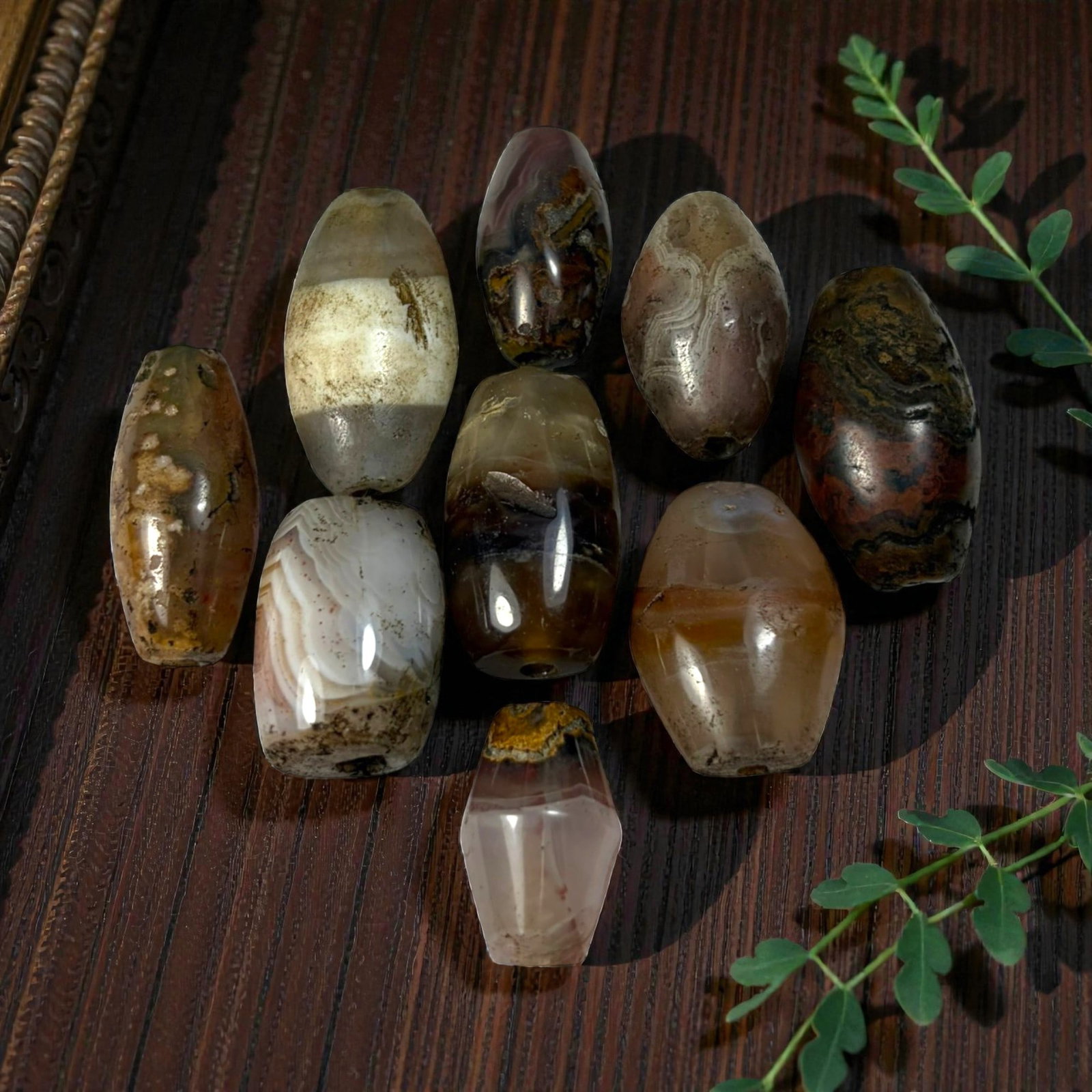 A Lot of 9 Himalayan Banded Agate Beads, Ancient to Antique Period, 48AN: Comprising lot of barrel and ovoid beads, each carved from banded agate with natural tonal variations, many displaying characteristic concentric, linear, and dendritic patterns. The surfaces exhibit s