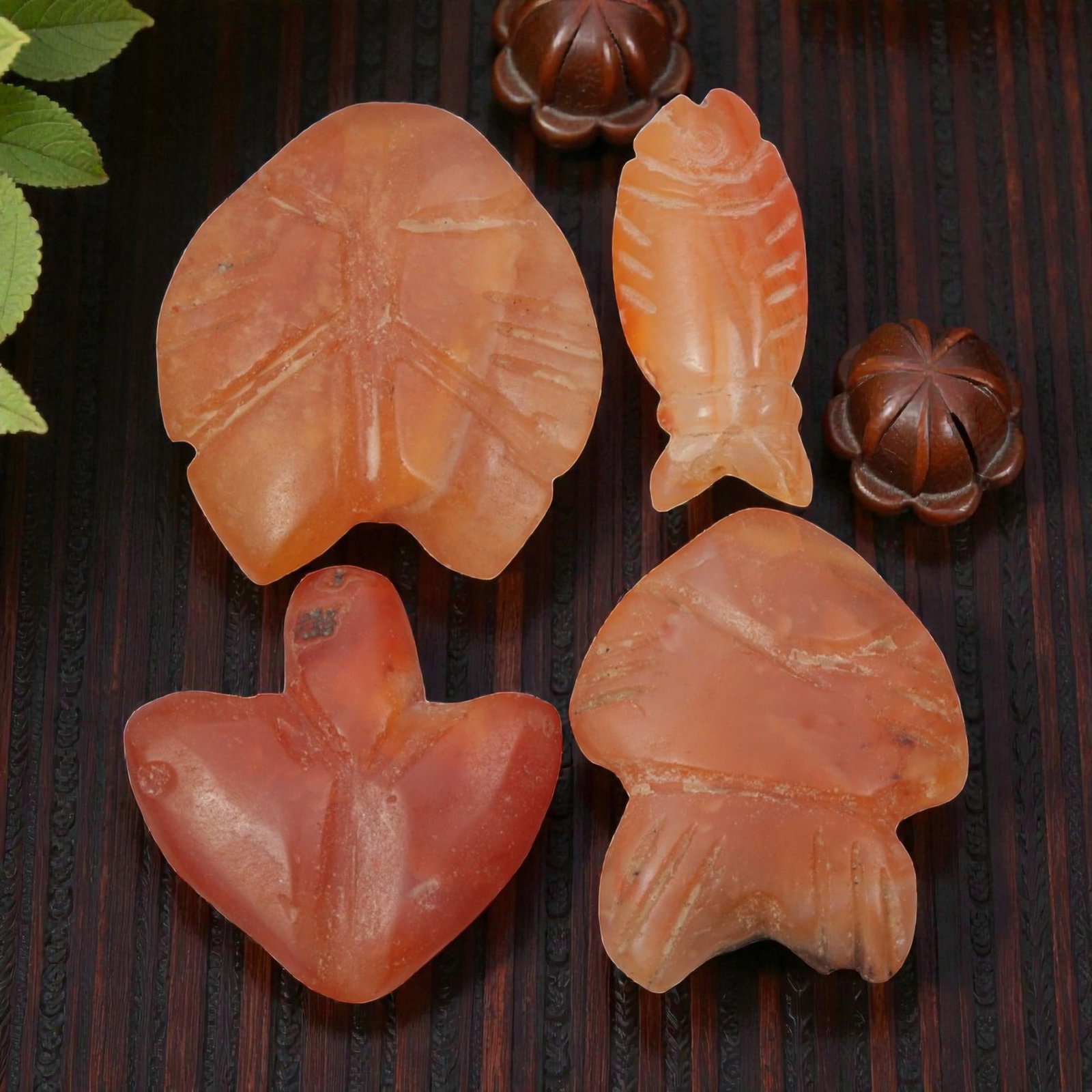 Lot of 4 Coptic Egyptian Carnelian Amulets, Circa Roman to Coptic Era, 17WS: The group consists of four carnelian amulets, each carved from orange-red stone with natural banding, translucency, and surface patina. The forms include stylized fish and bird/leaf motifs, with incis