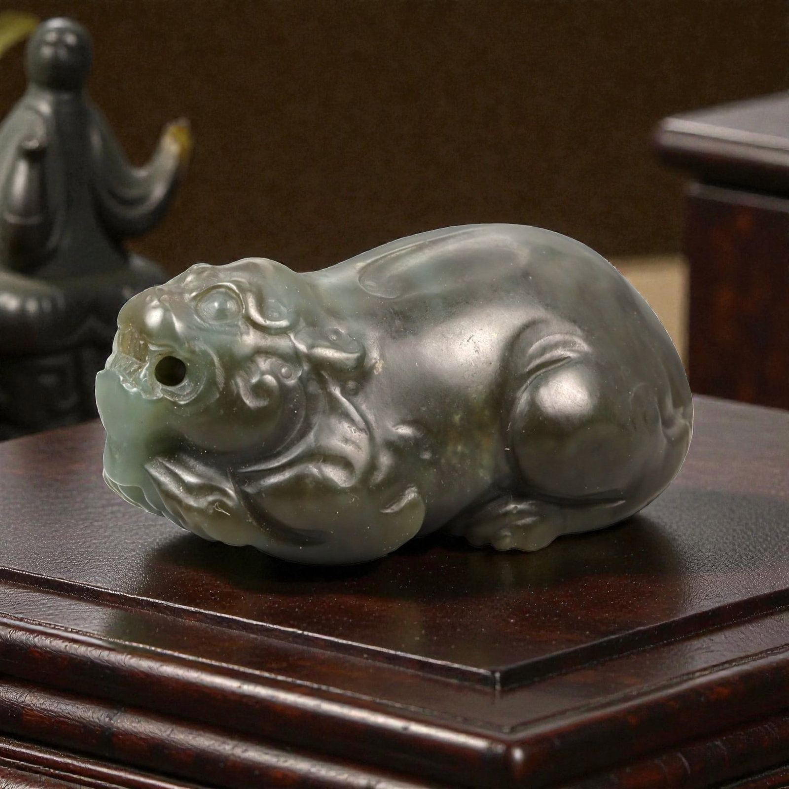 Chinese Jade Pixiu Beast - Carved Animal Figurine 5.5cm, 100ZC: Carved from green jade with areas of soft translucency and darker natural inclusions, this sculptural figure depicts a pixiu shown in a compact recumbent posture. The carving is executed fully in the 