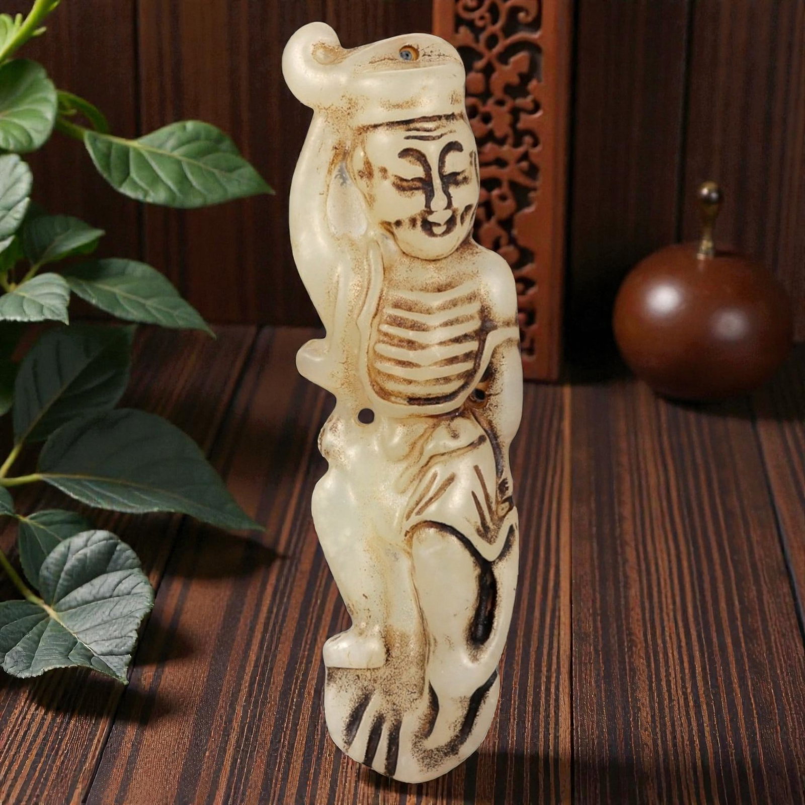 A Chinese Ancient Style Jade Stone Figural Pendant, 53FA: Carved from pale cream-colored stone with darker brown surface staining accentuating the incised details, the pendant depicts a standing human figure rendered in a simplified, elongated form. The figu