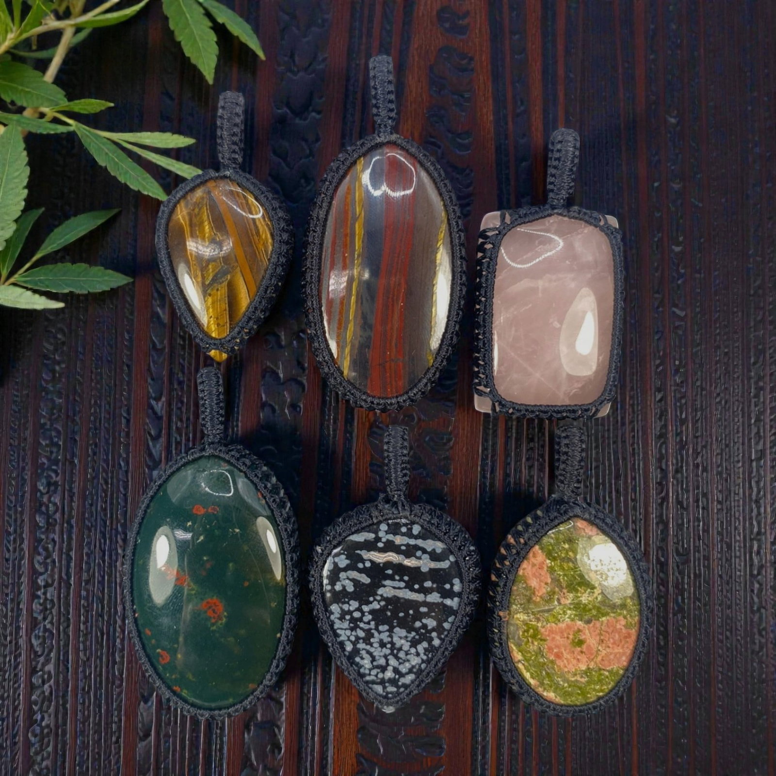 A Lot of 6 Macrame-Wrapped Gemstone Pendants, 11WS: This lot includes six handcrafted macrame-wrapped gemstone pendants, each measuring 5-7 cm in height. The collection features a diverse array of natural stones, including tiger's eye, banded ironstone