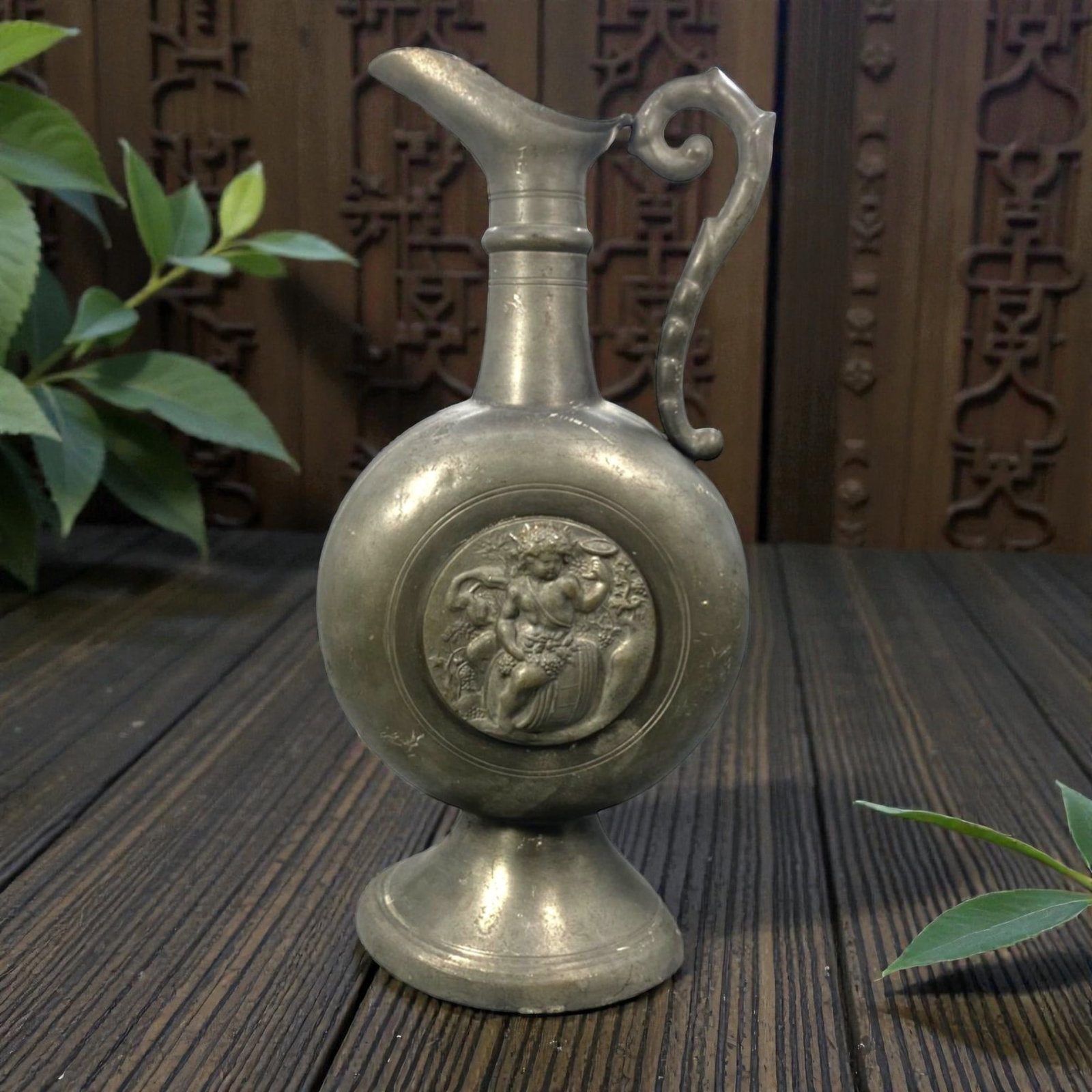 A Swiss Pewter Pitcher by Guggisberg Lugano, 20th Century, 55FK: The pitcher is formed in pewter with a globular body raised on a spreading circular foot, supporting a narrow cylindrical neck and a flaring pouring spout. A curved handle with a scrolling terminal is