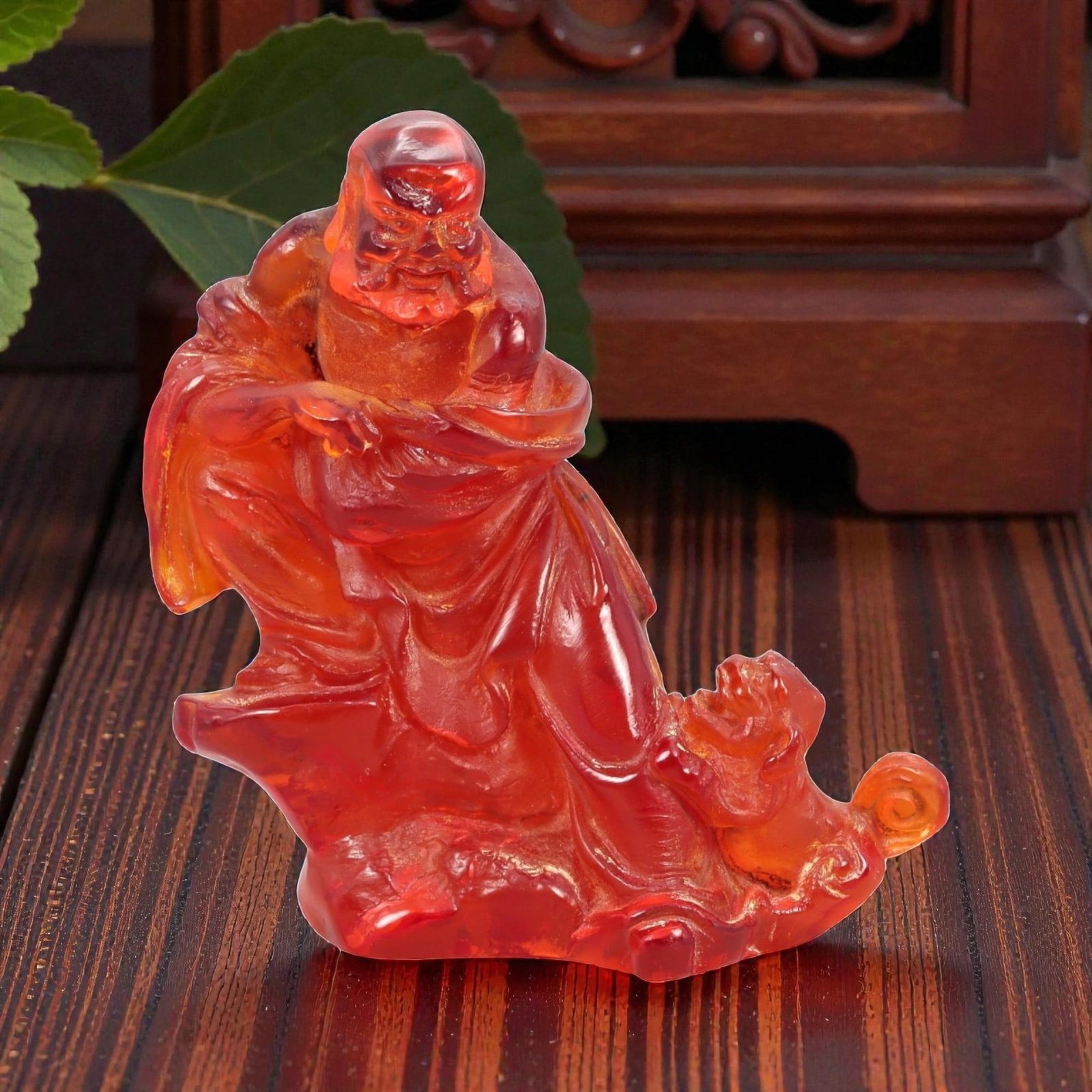 A Chinese Amber-Resin Figure of a Luohan, 20th Century, 40FH: Cast or carved from translucent amber-colored red resin with internal tonal variation and minor inclusions, the figure represents a standing luohan accompanied by a small attendant or symbolic creatur
