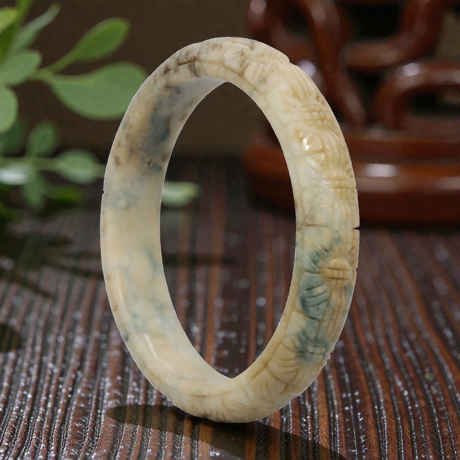 Natural Burmese Type A Carved Jadeite Jade Bangle Bracelet, 20th Century, 51ZL: A fine jadeite bangle of flattened circular form, intricately carved in relief with a continuous band of foliate and floral motifs. The stone displays a captivating variegated palette, featuring a cre