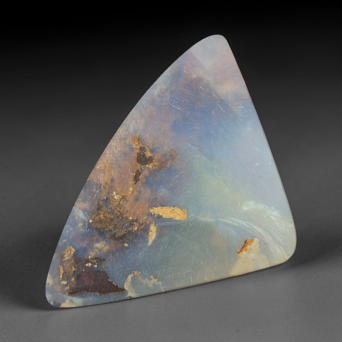7.27 Carats Soft Blue and Lavender Boulder Opal Cabochon - Natural Australian Stone, 63XM: This substantial boulder opal cabochon features a soft, milky base of pale blue and lavender, infused with delicate, iridescent undertones that shift with light. The stone's triangular form showcases 