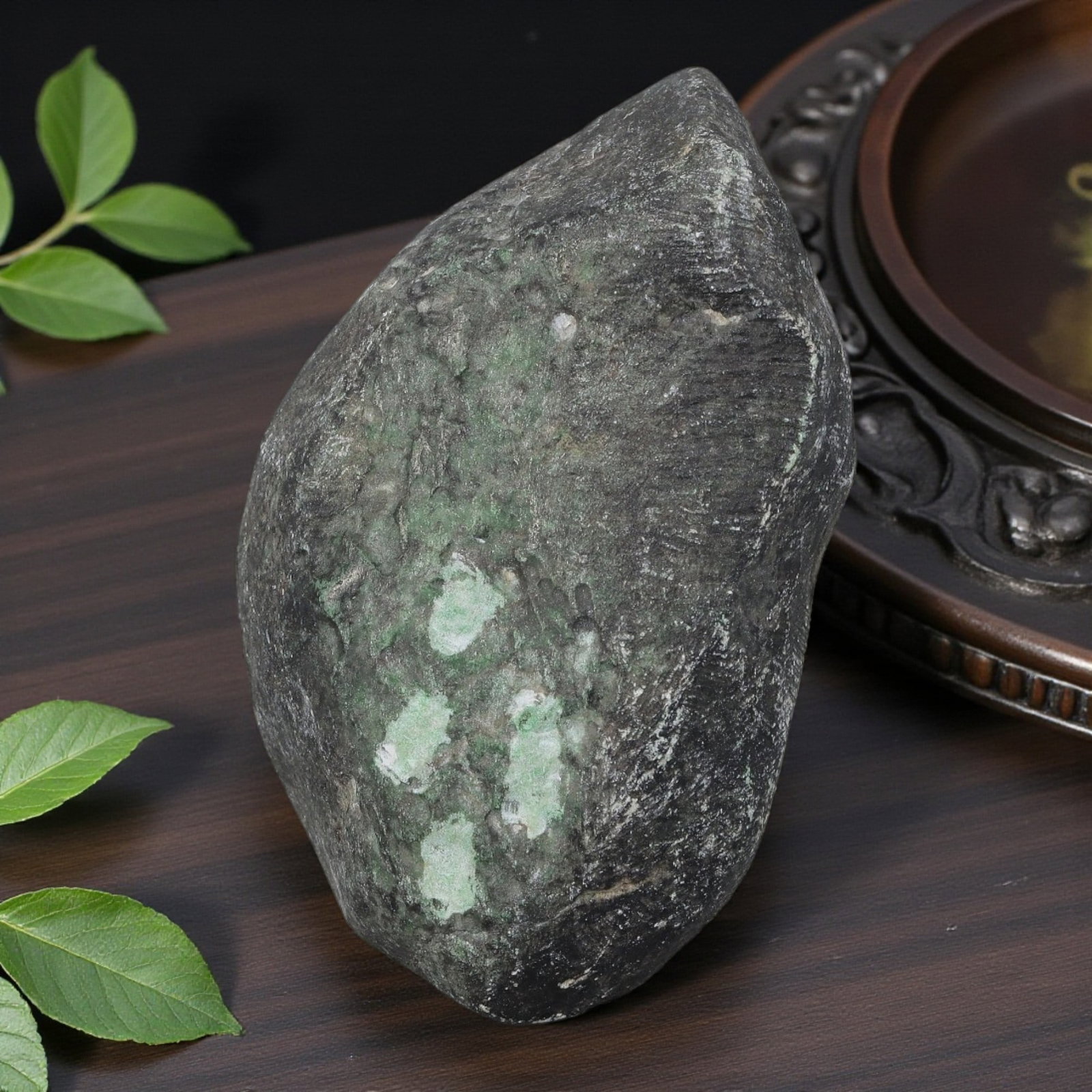 350Ct Natural Type A Burmese Jadeite Jade Rough Stone - Green Raw Material, 5ZB: Natural Type A Burmese jadeite rough stone, displaying scattered light green mineral deposits visible through its dark, naturally weathered outer skin. The stone retains its uncut, rounded raw form, s
