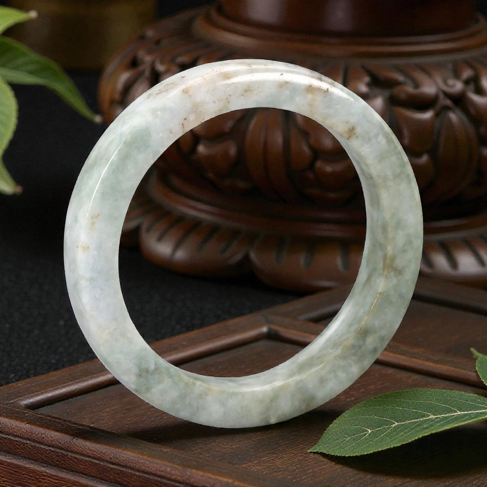 Natural Burmese Type A Jadeite Jade Bangle Bracelet, 20th Century, 85ZK: Carved from jadeite jade with a pale greenish-white base and scattered light brownish inclusions, the bangle is formed as a continuous circular band with a rounded cross-section. The surface is smooth