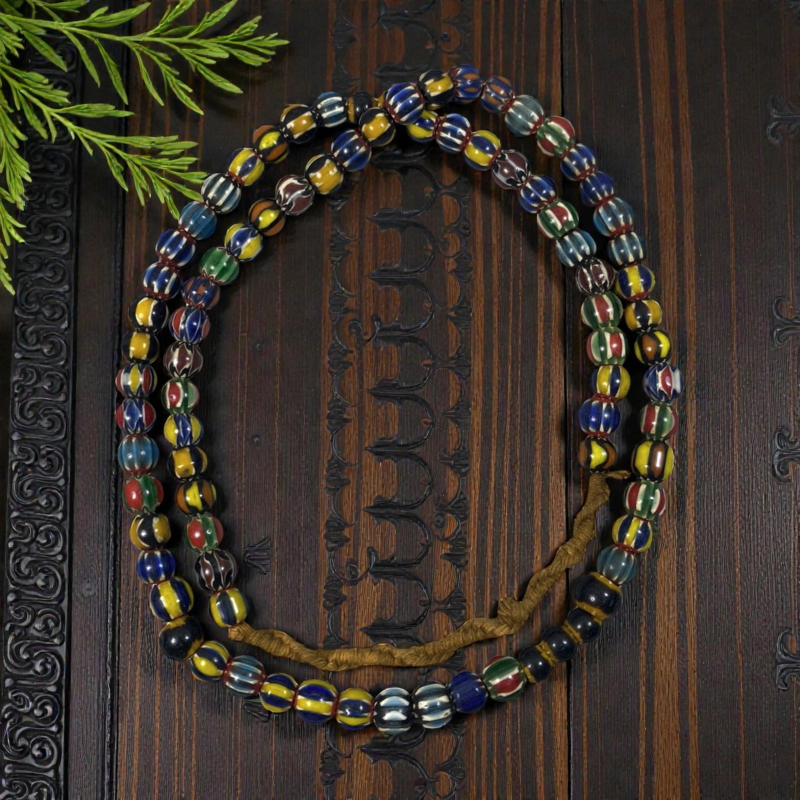 Strand of Antique Chevron Glass Beads, Unstrung, 64AH: A single strand of unstrung antique chevron glass beads, measuring approximately 30 cm in length. The strand features round beads adorned with vibrant, multicolored striped chevron patterns, character