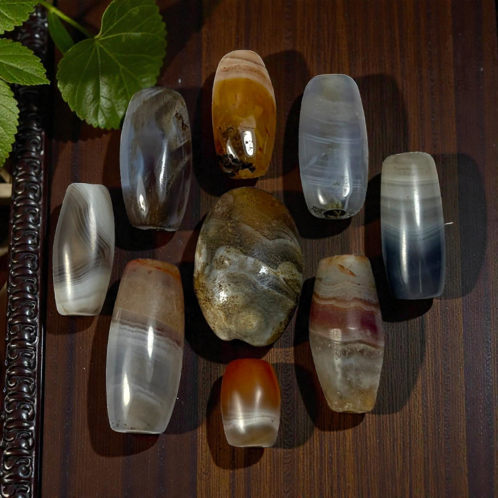 A Lot of 9 Himalayan Banded Agate Beads, Ancient to Antique Period, 53AN: Comprising lot of barrel and ovoid beads, each carved from banded agate with natural tonal variations, many displaying characteristic concentric, linear, and dendritic patterns. The surfaces exhibit s