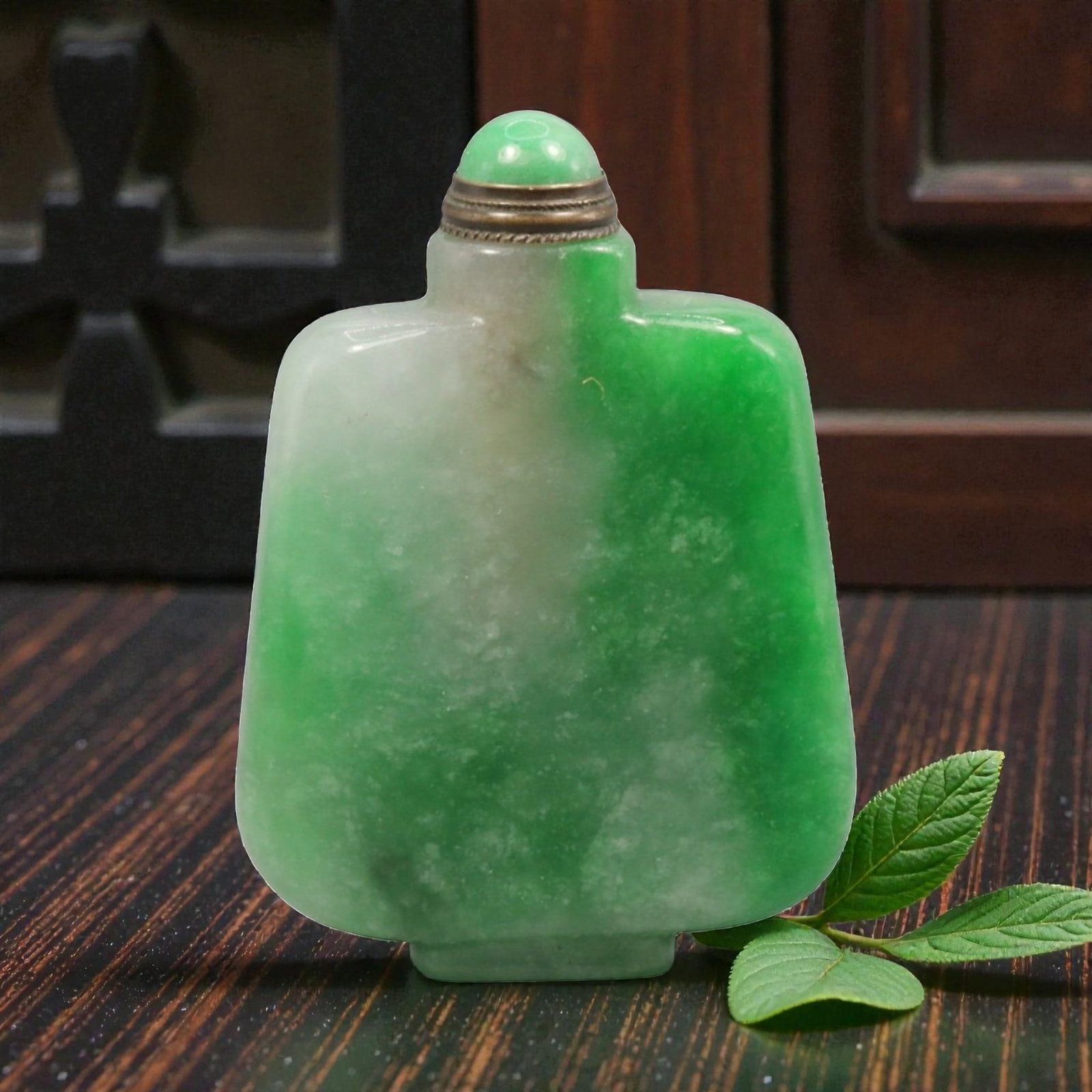 A Chinese Jadeite Jade Snuff Bottle, 20th Century, 27YC: The bottle is carved from jadeite jade with mottled green and pale white coloration, the stone displaying natural clouding and tonal transitions. It is formed with a flattened rectangular body with ro