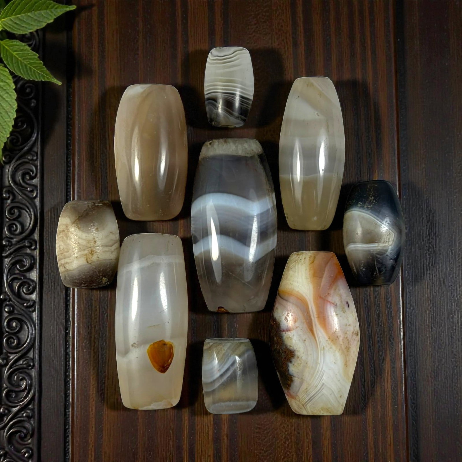 A Lot of 9 Himalayan Banded Agate Beads, Ancient to Antique Period, 24YD: Comprising lot of barrel and ovoid beads, each carved from banded agate with natural tonal variations, many displaying characteristic concentric, linear, and dendritic patterns. The surfaces exhibit s