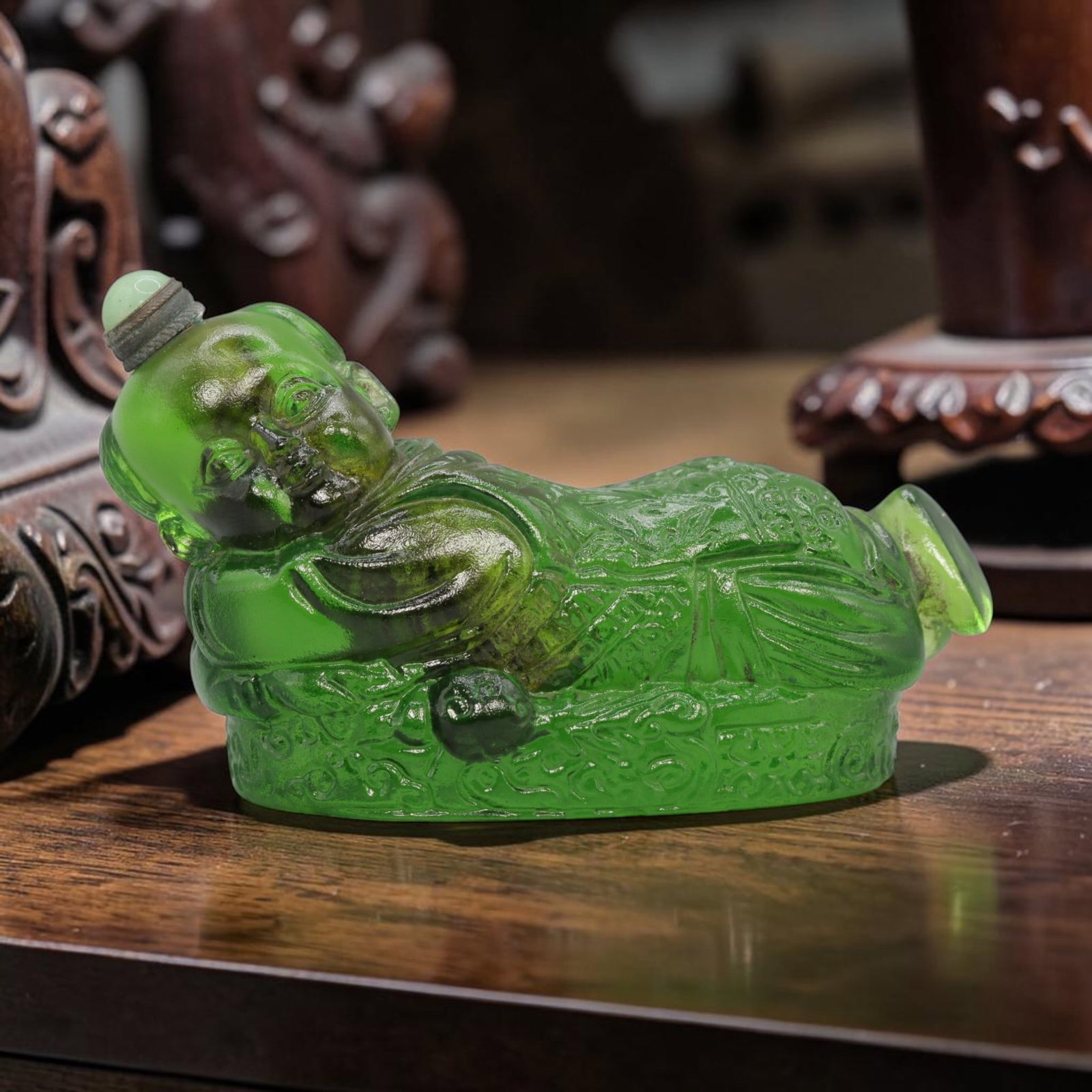 Vintage Chinese Green Liuli Glass Snuff Bottle - Reclining Child Figurine, 80YF: Crafted from translucent rich green liuli glass, this vintage Chinese snuff bottle is modelled as a reclining child figure. The glass exhibits a vibrant green hue with subtle internal tonal variations