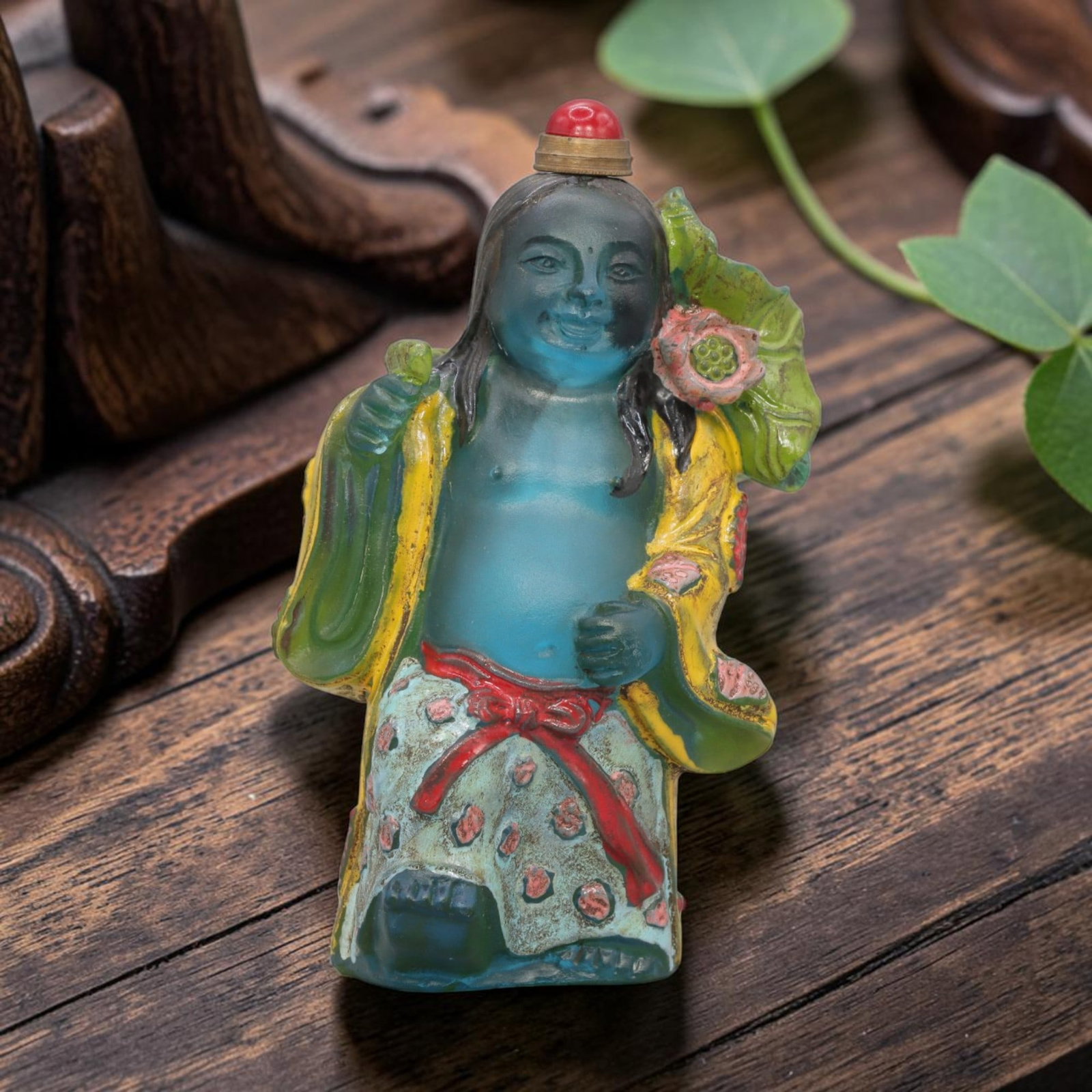 Vintage Chinese Enameled Liuli Snuff Bottle - Figure, 70YF: Crafted from translucent blue-toned liuli glass, this snuff bottle depicts a standing folk figure with a bare torso, long hair, and a smiling expression. The figure's robes are adorned with hand-paint