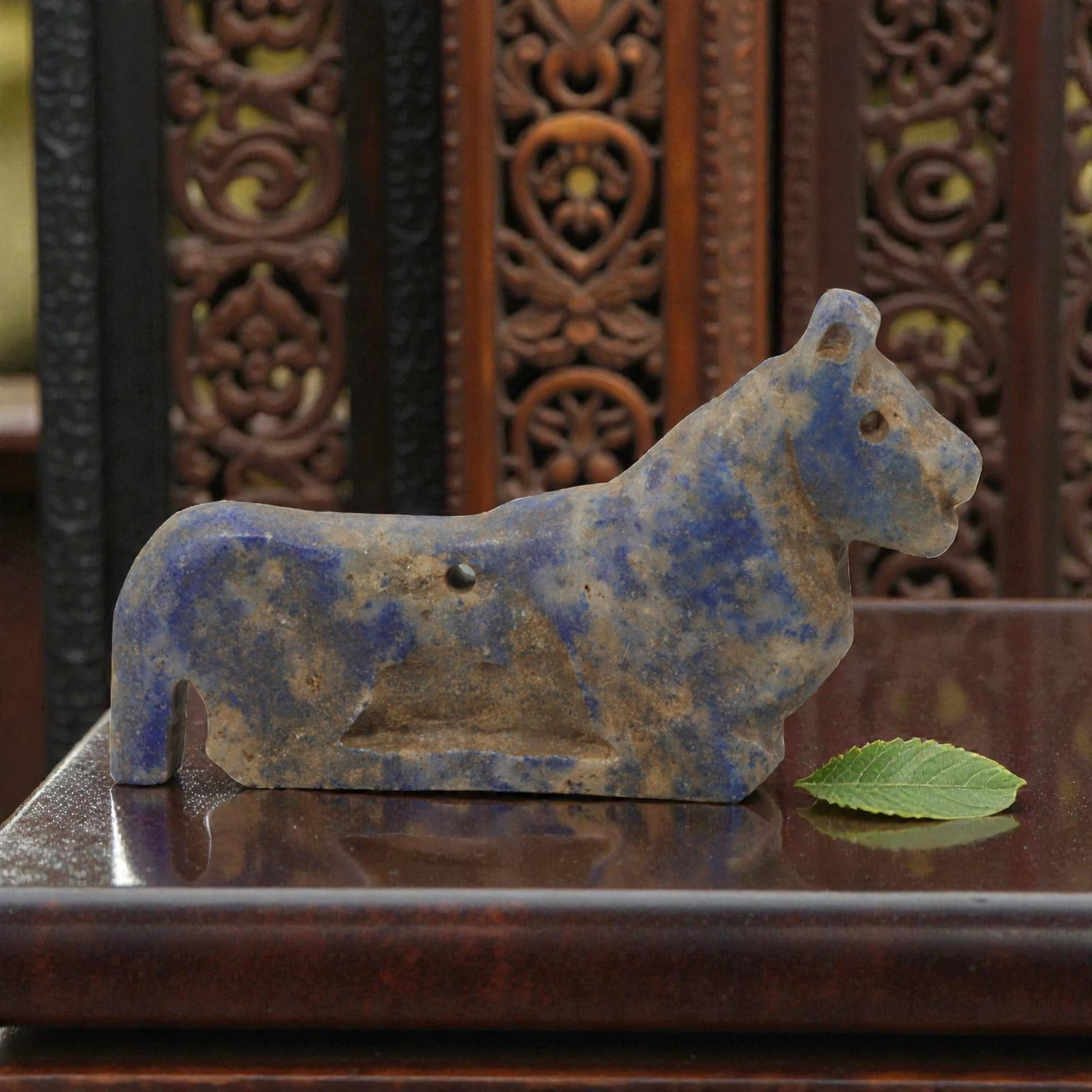 Ancient Near Eastern Style Lapis Lazuli Recumbent Feline Amulet, 51WM: A single ancient Near Eastern-style amulet, carved from lapis lazuli in the form of a recumbent feline (likely a lion or similar big cat). The piece features simplified facial features, stylized ears,