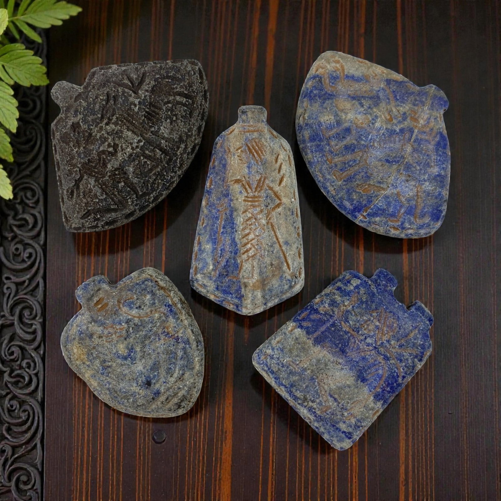 A Lot of 5 Ancient Near Eastern Lapis Lazuli Amulets, 11AC: The group comprises five amulets carved from lapis lazuli, with tones ranging from deep blue to weathered grey-blue, interspersed with natural mineral inclusions and surface patina consistent with ant