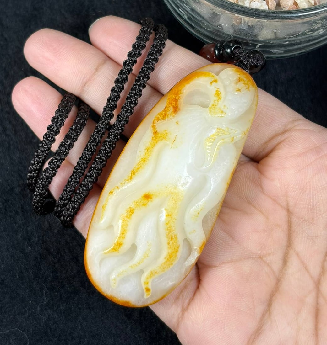 Natural Xinjiang Hetian White Nephrite Ginseng Carved Pendant With Natural Orange Russet Skin, 8AT: Hand-carved from genuine Xinjiang Hetian mutton fat white nephrite seed jade, this elongated oval pendant measures 7 x 3 cm, retaining its natural river-worn pebble shape with striking warm orange rus