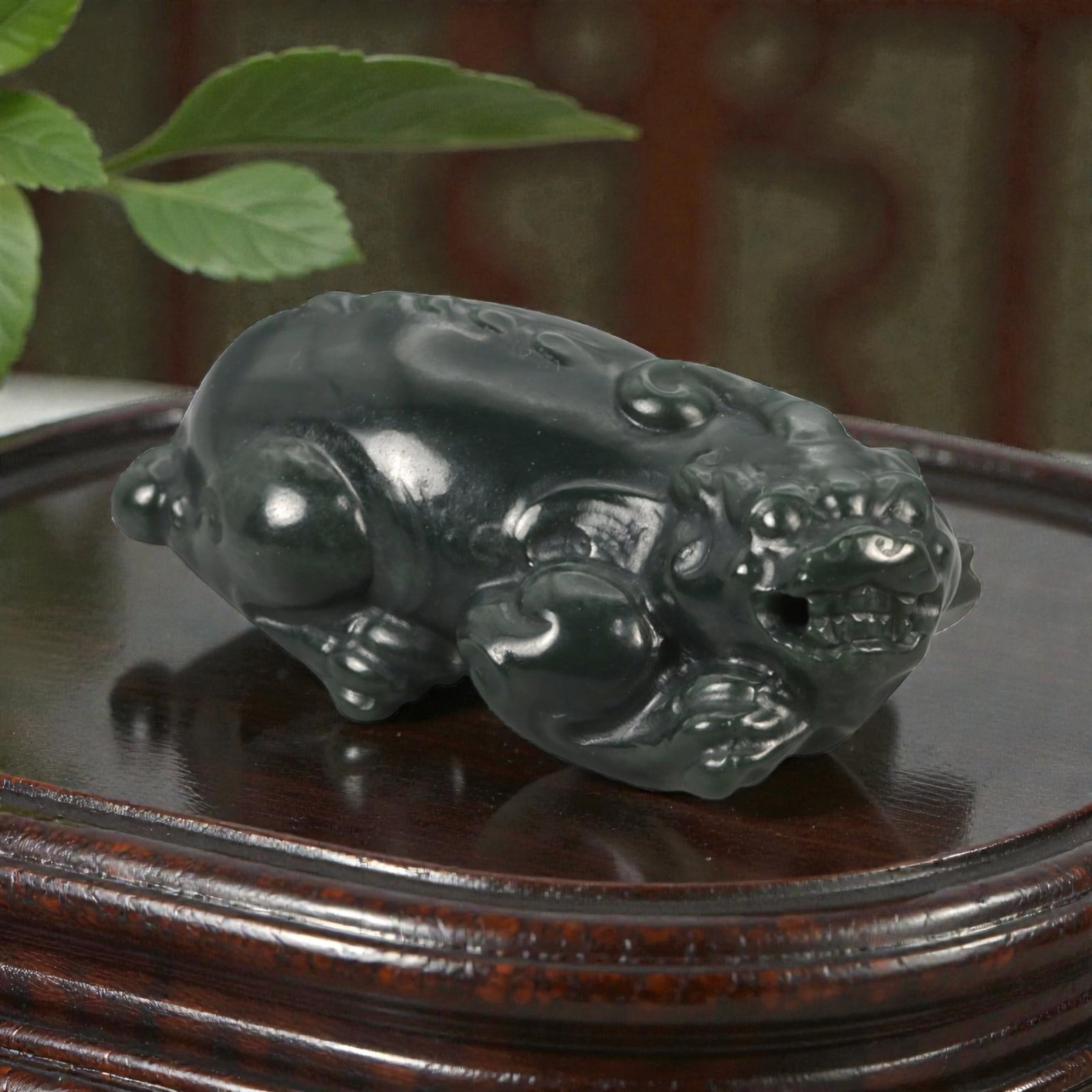 A Chinese Nephrite Jade Pixiu Figure, 20th Century, 94FB: Carved from dark green nephrite jade with areas of translucency and a high, even polish, the figure is modeled as a recumbent pixiu, shown with the head turned slightly to one side. The creature is re