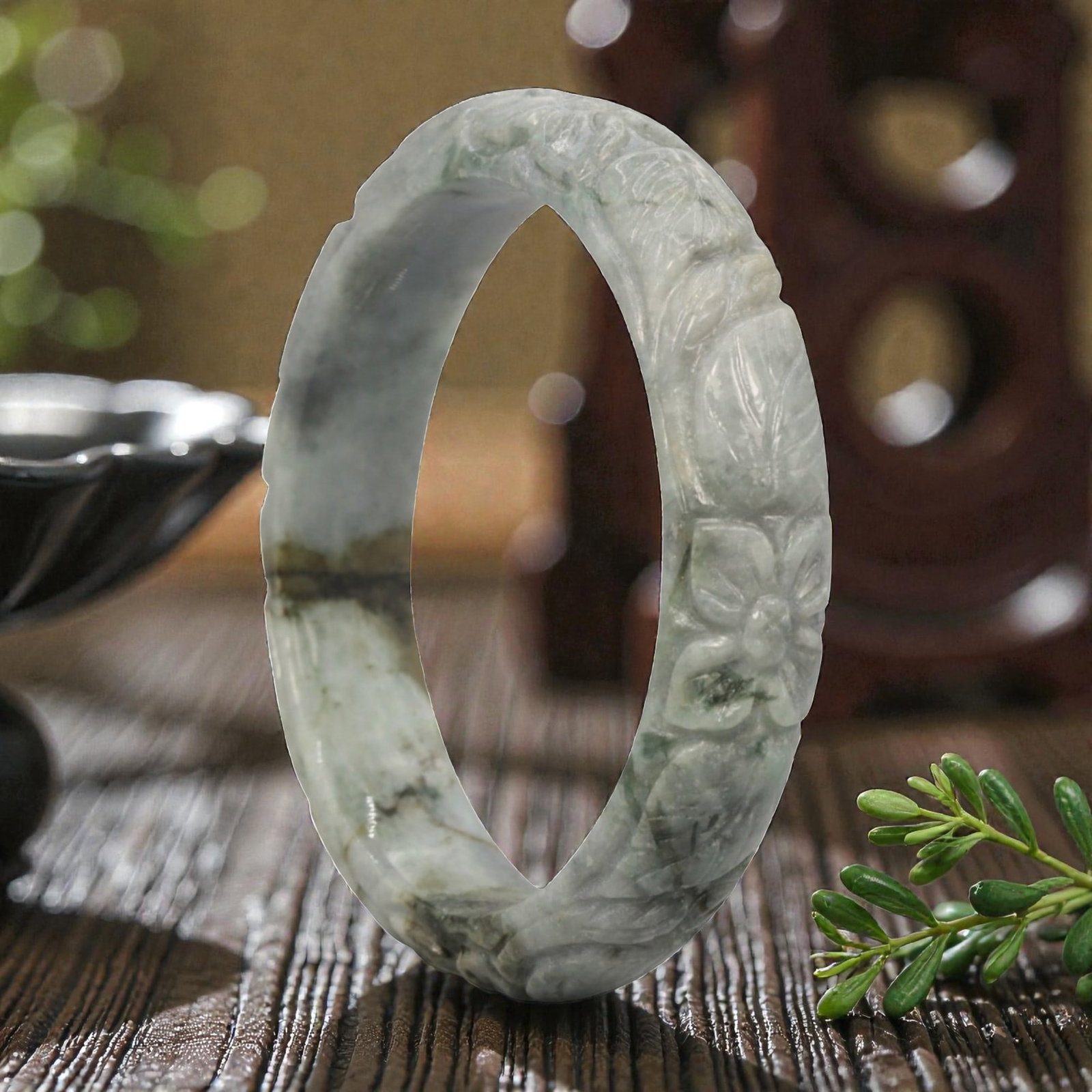 Natural Burmese Type A Carved Jadeite Jade Bangle Bracelet, 20th Century, 45ZL: A fine jadeite bangle of flattened circular form, masterfully carved in relief with a continuous band of floral blossoms and scrolling foliate motifs. The stone exhibits a translucent pale greenish-gr