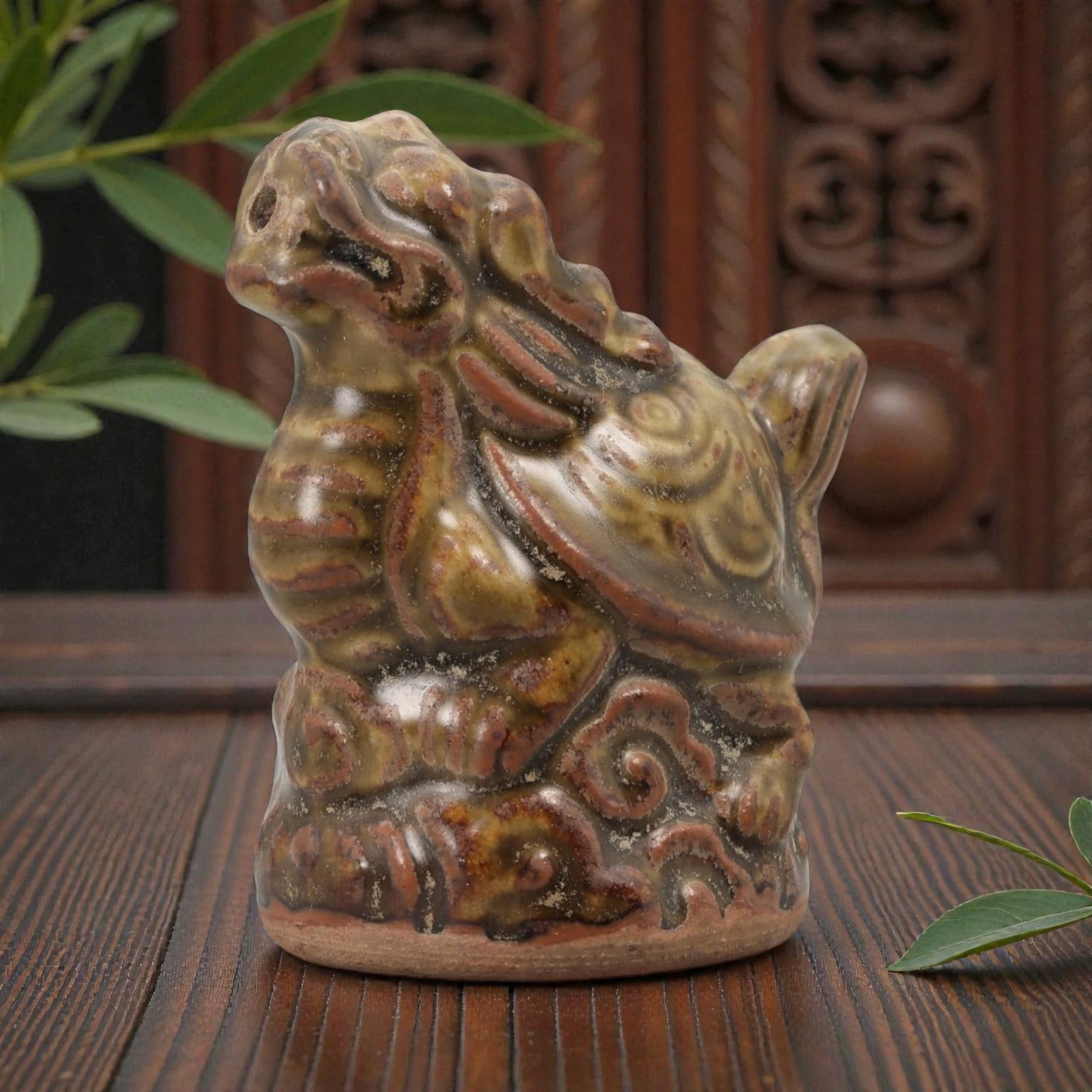 A Chinese Glazed Ceramic Bixi Figure, 20th Century, 78FG: Modeled from ceramic and covered with a mottled glaze in olive green, brown, and reddish tones, the figure represents bixi, the mythical creature combining the body of a tortoise with the head of a dr